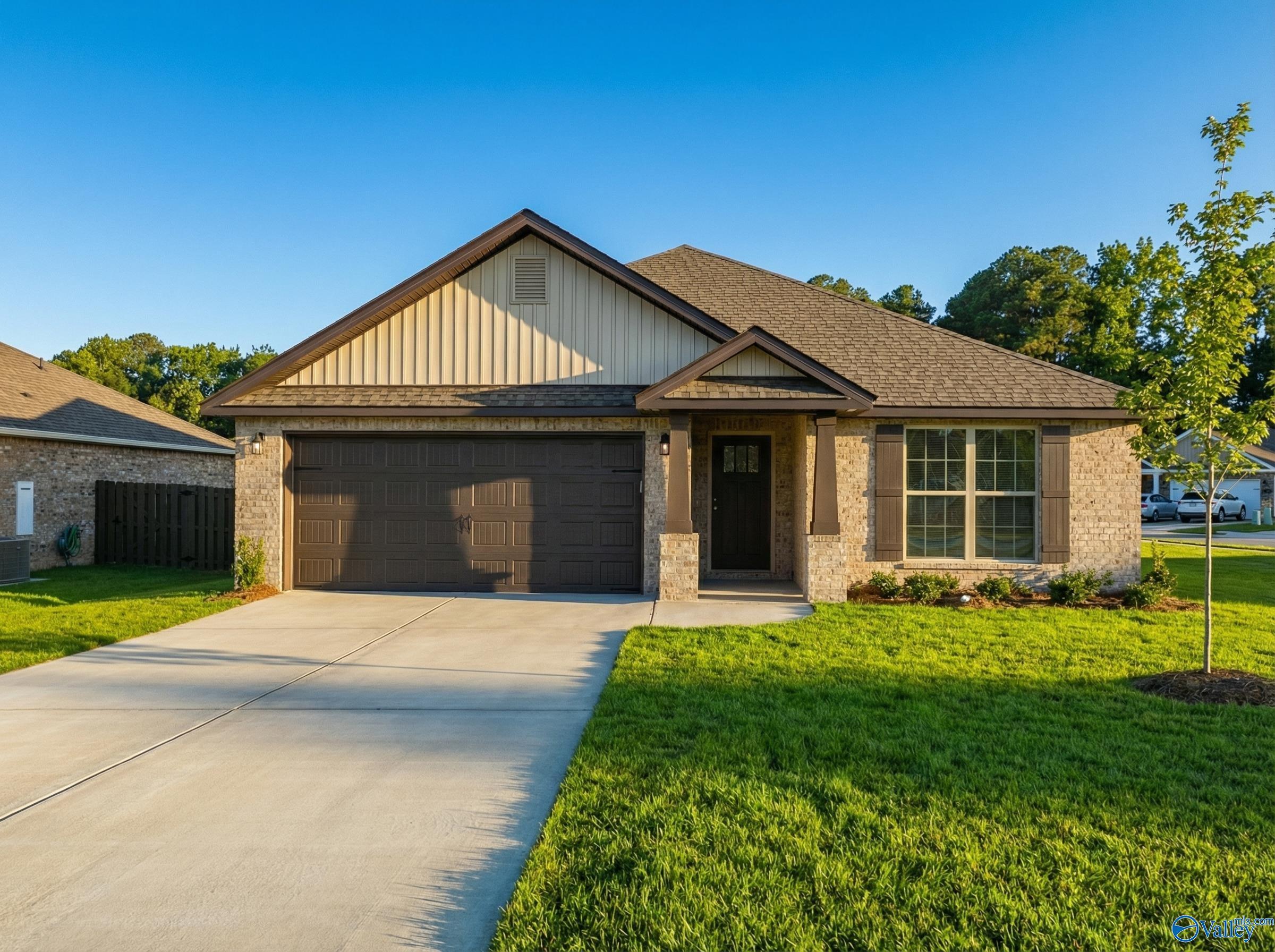 Tan brick 1-story home with 2-car garage, shingle roof, front porch, and lush green yard in The Highlands, Arab, Alabama - The Daphne C by Davidson Homes