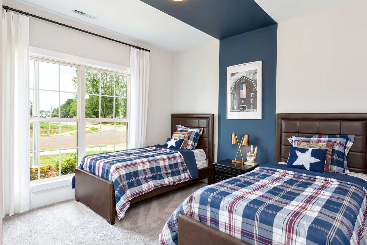Boys' bedroom with twin beds, navy plaid bedding, accent wall, and large windows at Williams Pointe in Huntsville AL