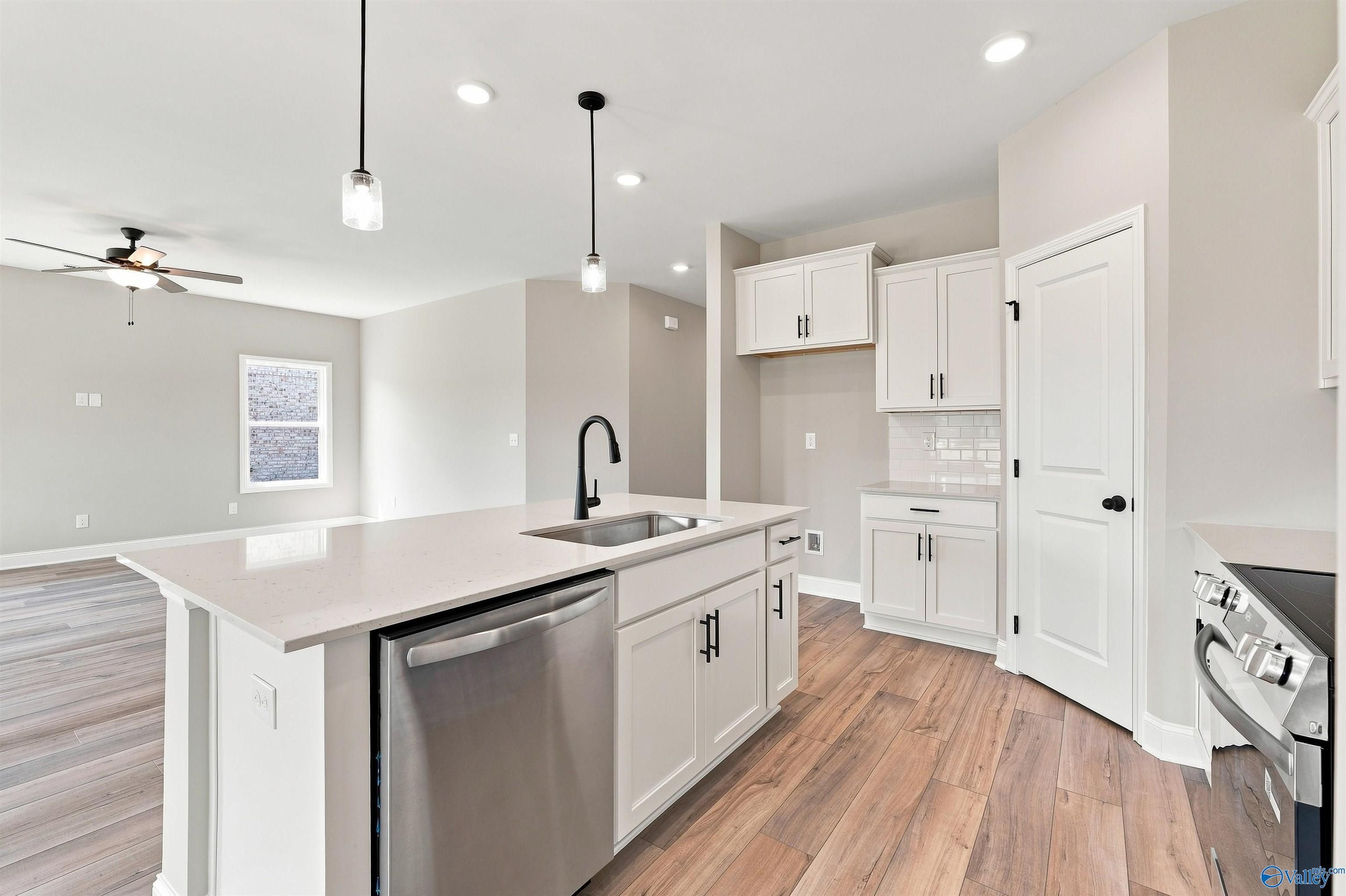 Modern kitchen with white shaker cabinets, quartz island, and stainless appliances in Davidson Homes The Franklin C, Toney, AL