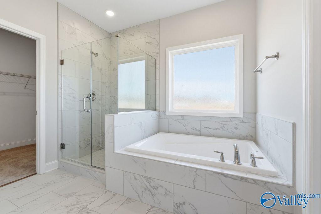 Elegant master bathroom featuring freestanding soaking tub, glass walk-in shower, marble tiles in Davidson Homes The Harrison, Hartselle AL