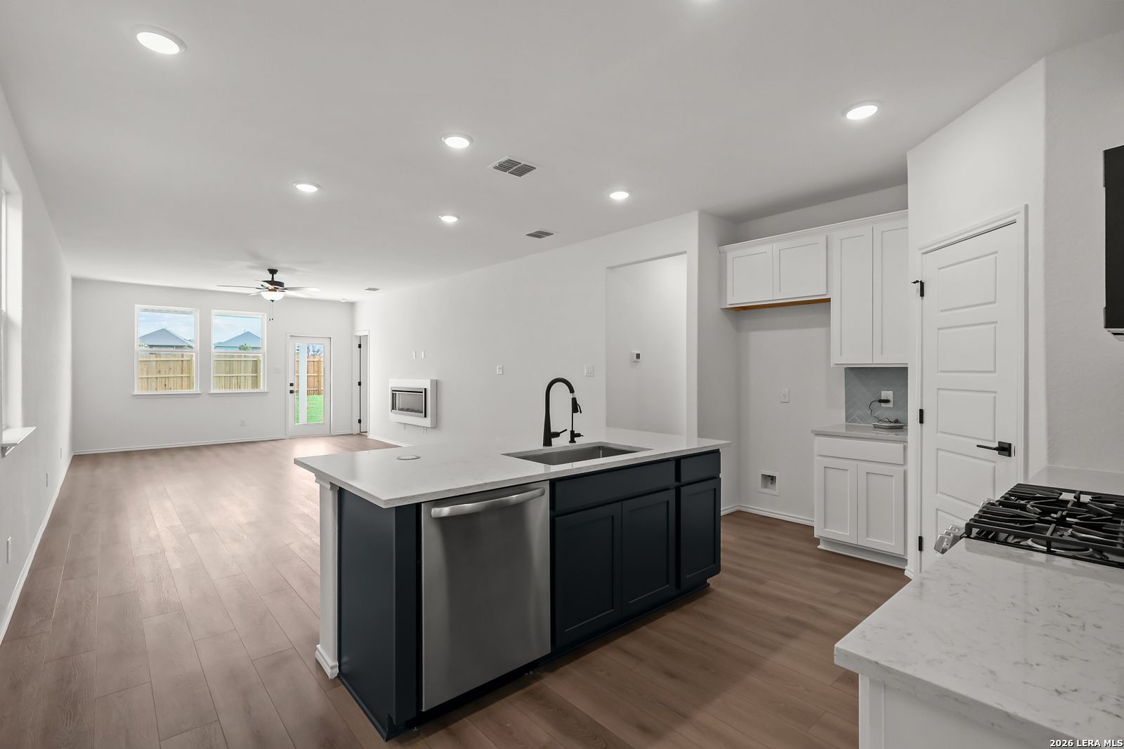 Open-concept kitchen with navy island, white cabinets, and stainless appliances in Davidson Homes Pinecrest F, San Antonio, TX