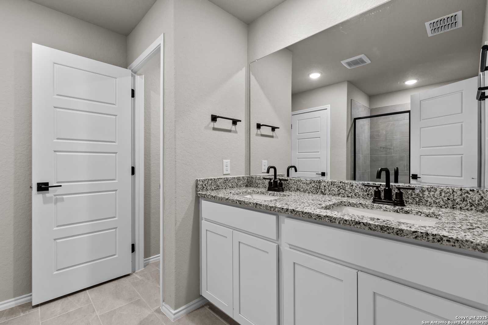 Modern master bathroom featuring double vanity with granite countertops and walk-in shower in Davidson Homes The Murray I, San Antonio