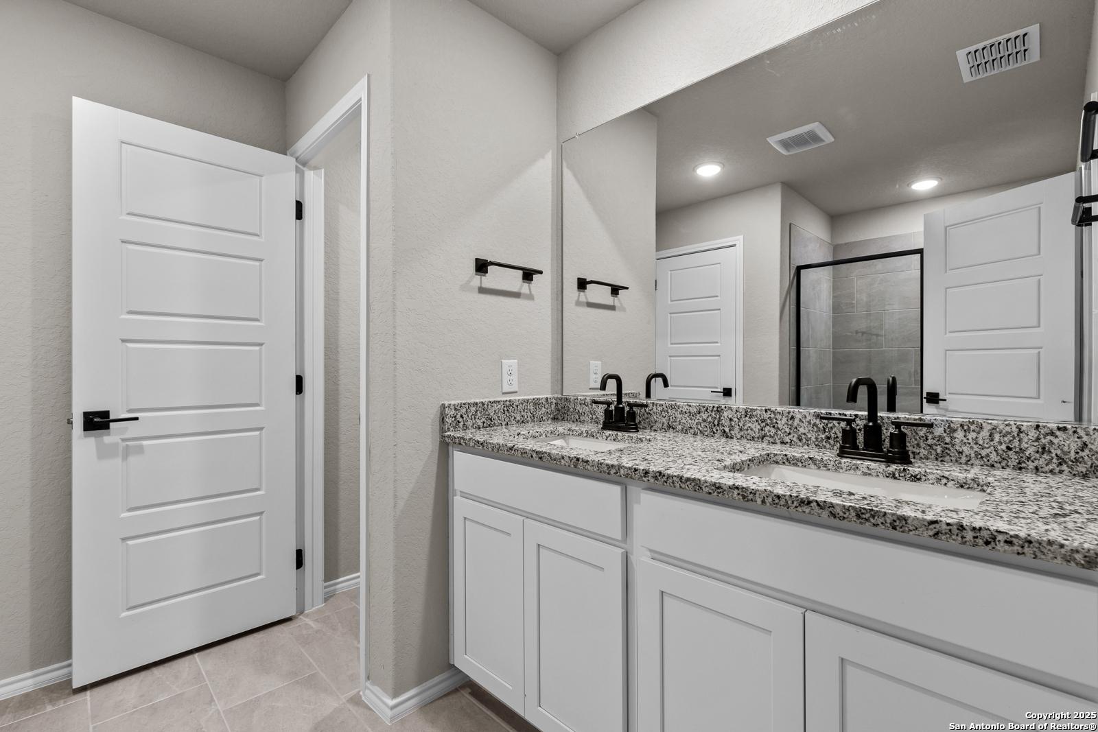 Modern master bathroom featuring double vanity with granite countertops and walk-in shower in Davidson Homes The Murray I, San Antonio