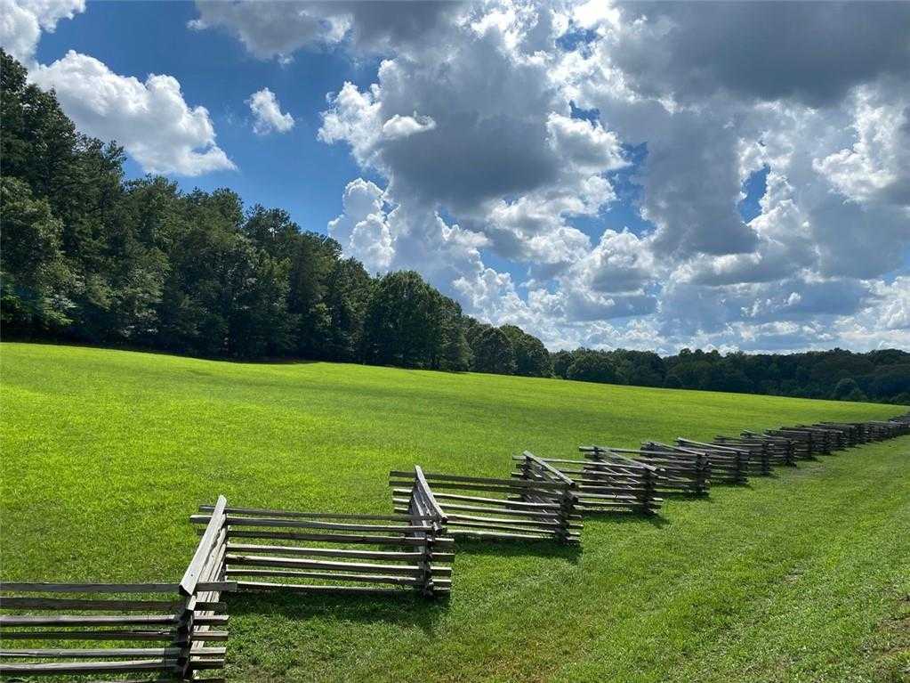 Scenic green pastures with wooden split-rail fences and lush woods under blue skies in The Village at Shallowford, Kennesaw, Georgia