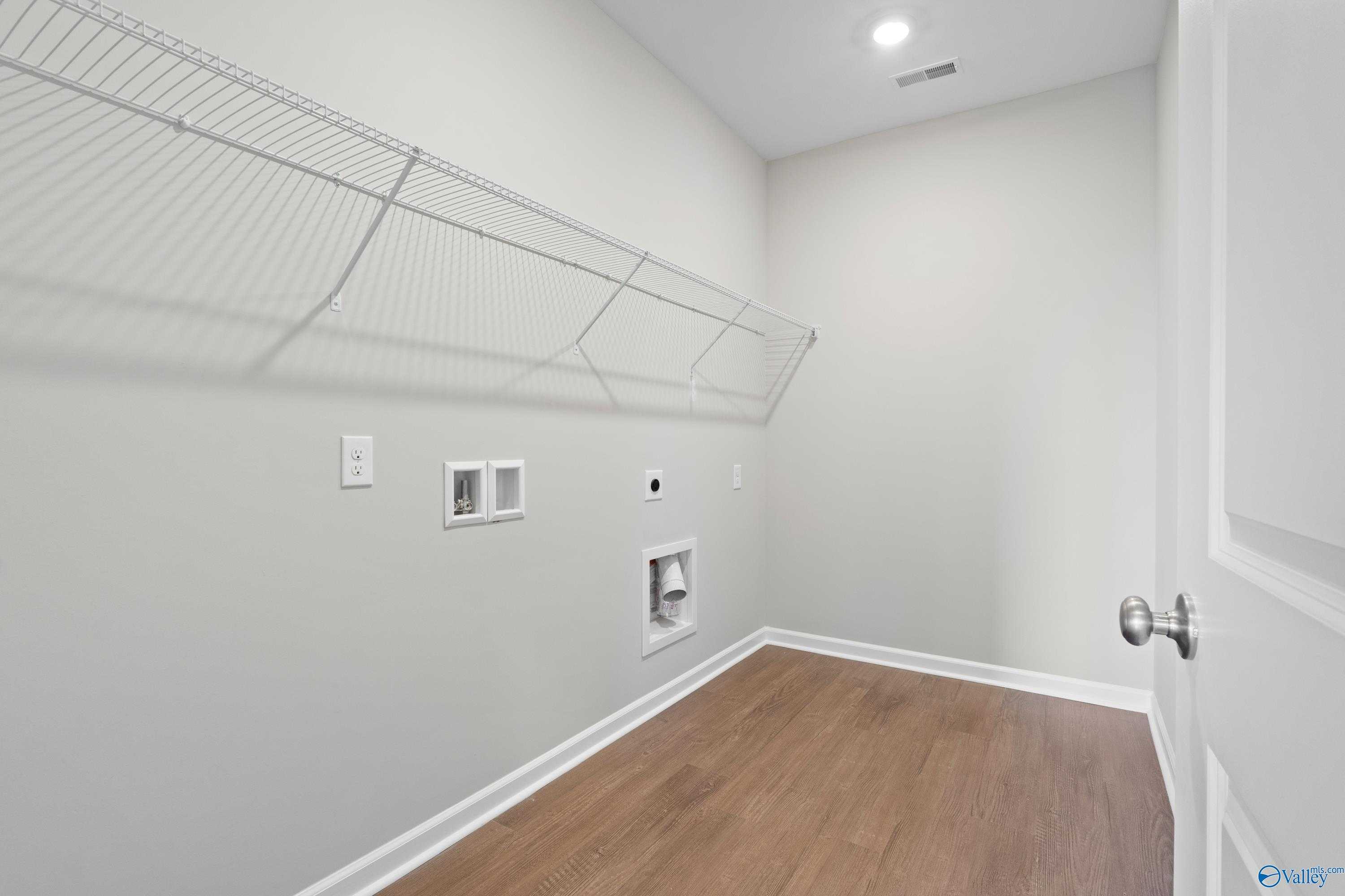 Spacious laundry room with wire shelving, washer-dryer hookups, and hardwood floors in Davidson Homes The Dorado, Athens, Alabama