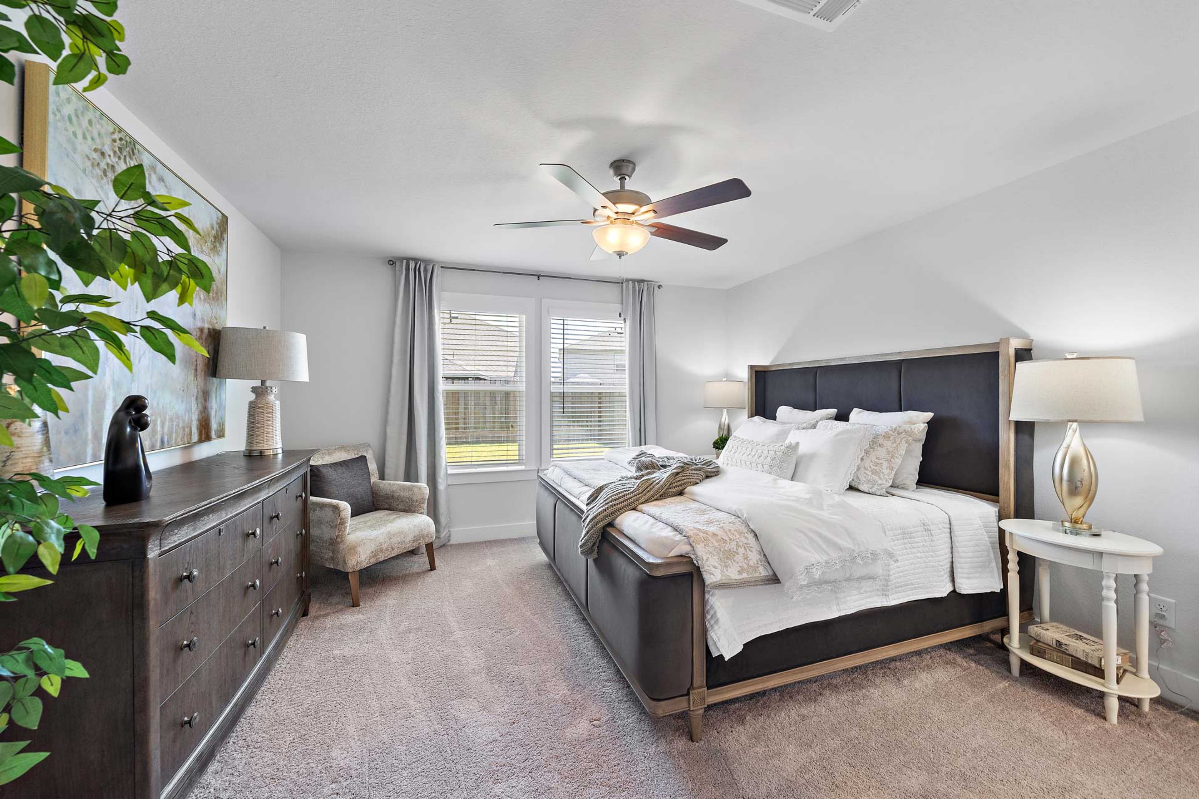 Spacious master bedroom at Haven at Kieth Harrow in Cypress Texas with king bed, ceiling fan, large windows, and plush carpet