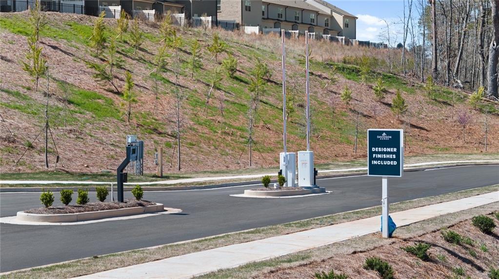 Davidson Homes sign at The Bluffs entrance with hillside craftsman townhomes, landscaped street in Canton, Georgia