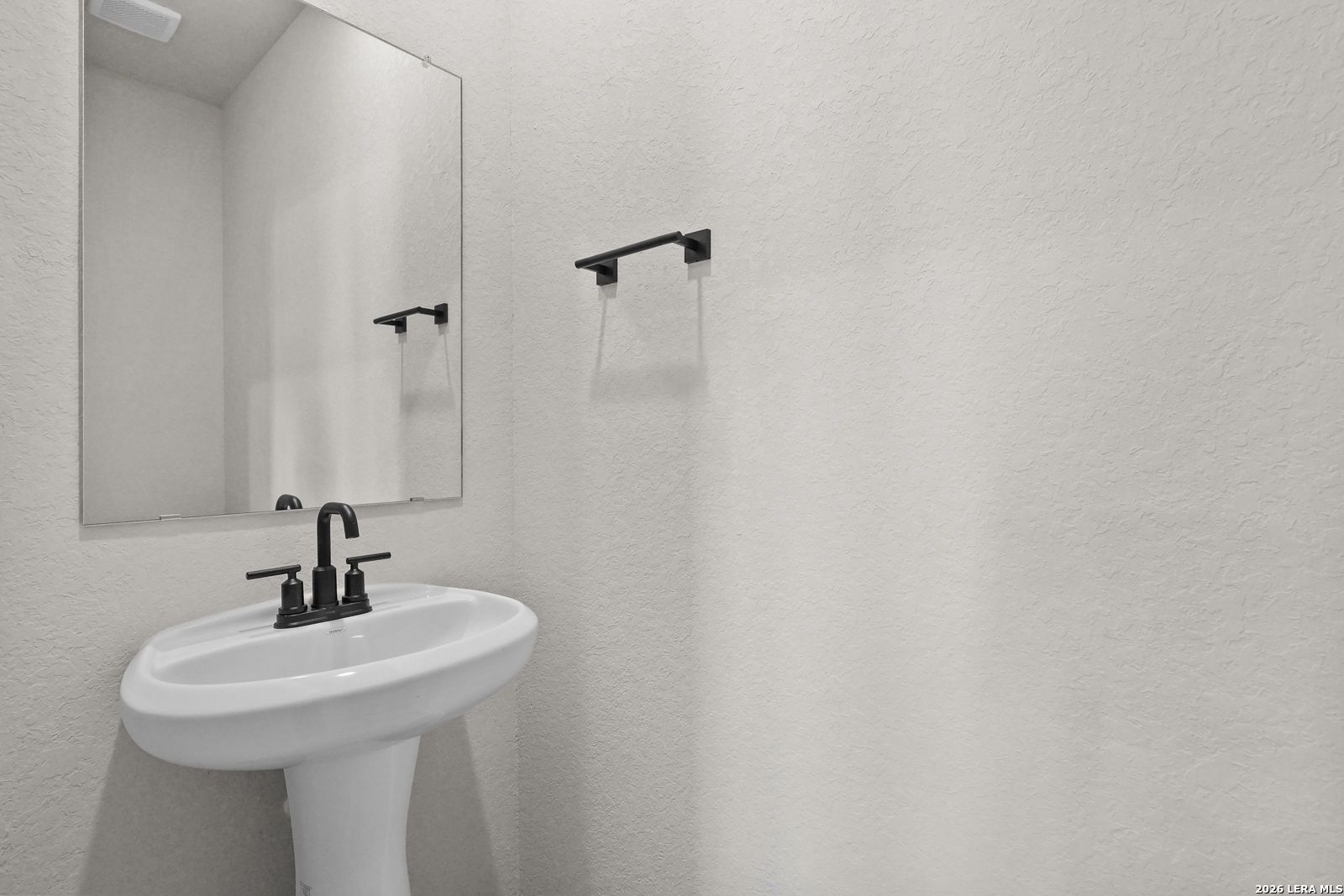 White pedestal sink with matte black faucet and mirror in half bath at Davidson Homes The Glenwood E, Comanche Ridge, San Antonio