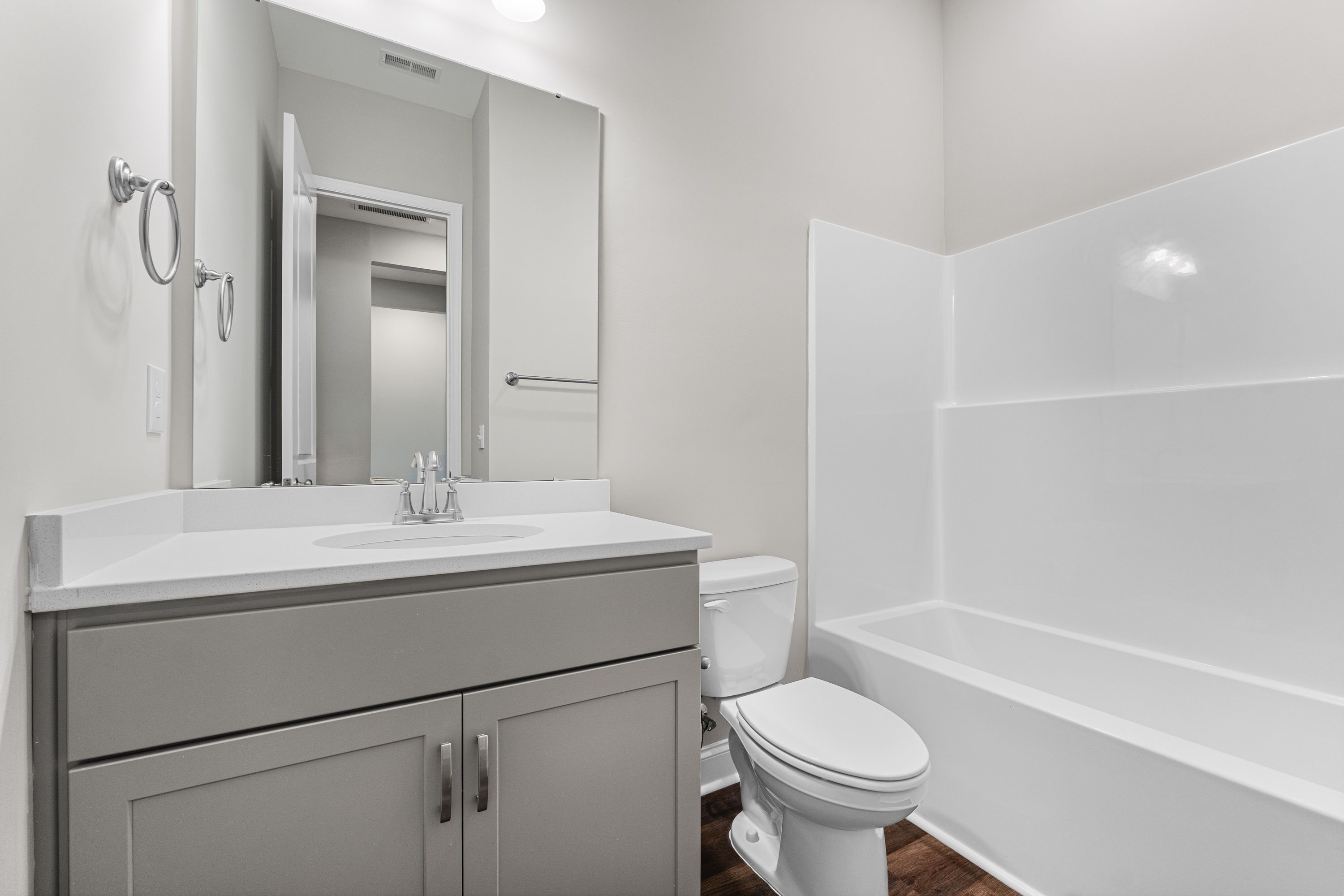 Spacious master bathroom in The Arcadia E with white tub-shower combo, gray vanity, and modern fixtures