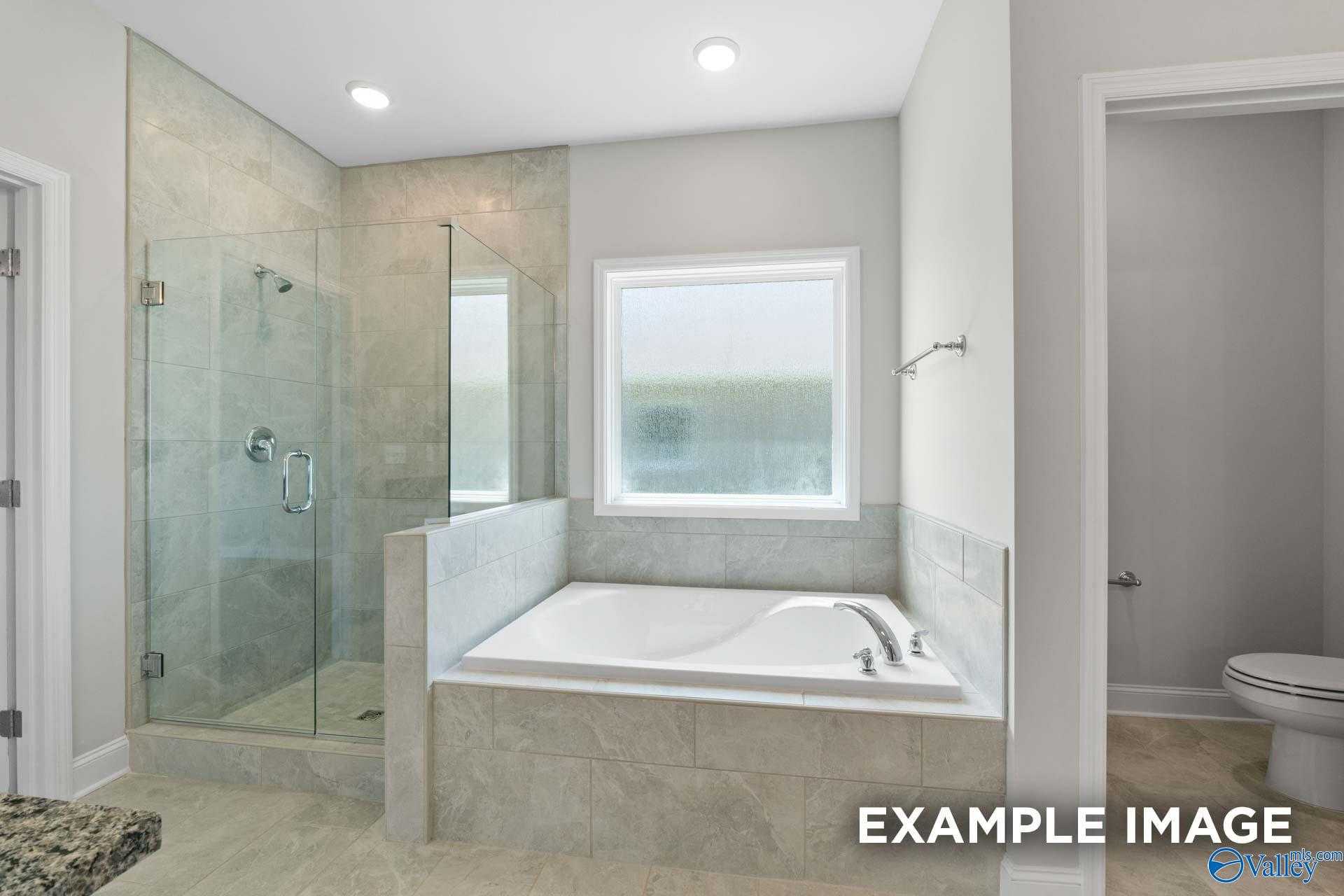 Luxurious master bathroom with frameless glass shower, soaking tub, and large window in Davidson Homes The Lanier, Pikes Ridge, Meridianville, Alabama