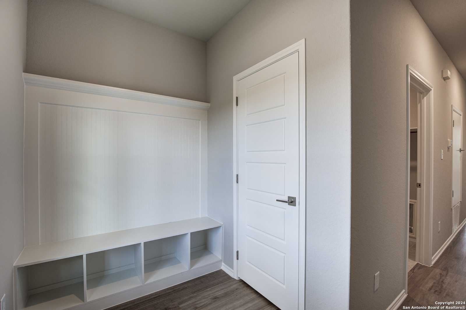 Built-in entryway bench with white storage cubbies and locker shelving in Davidson Homes The Frio B, San Antonio, Texas