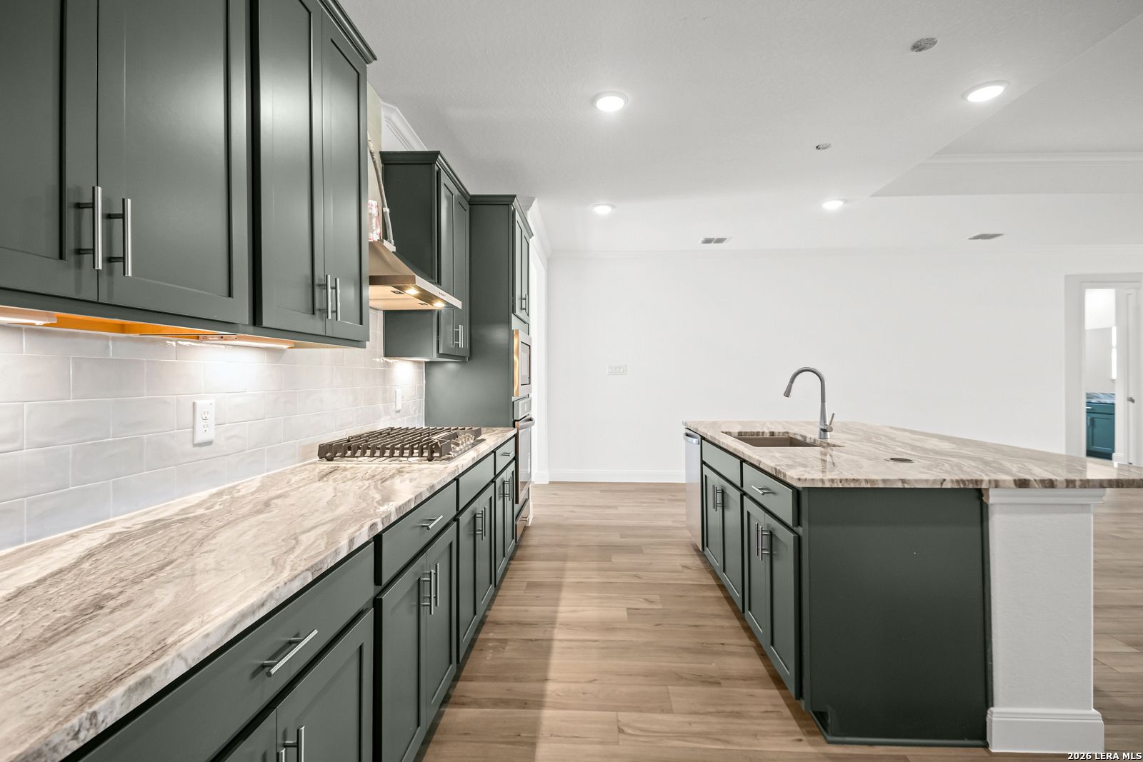 Modern kitchen with dark green cabinets, marble countertops, and island in The Lanier G plan at The Reserve at Potranco Oaks.