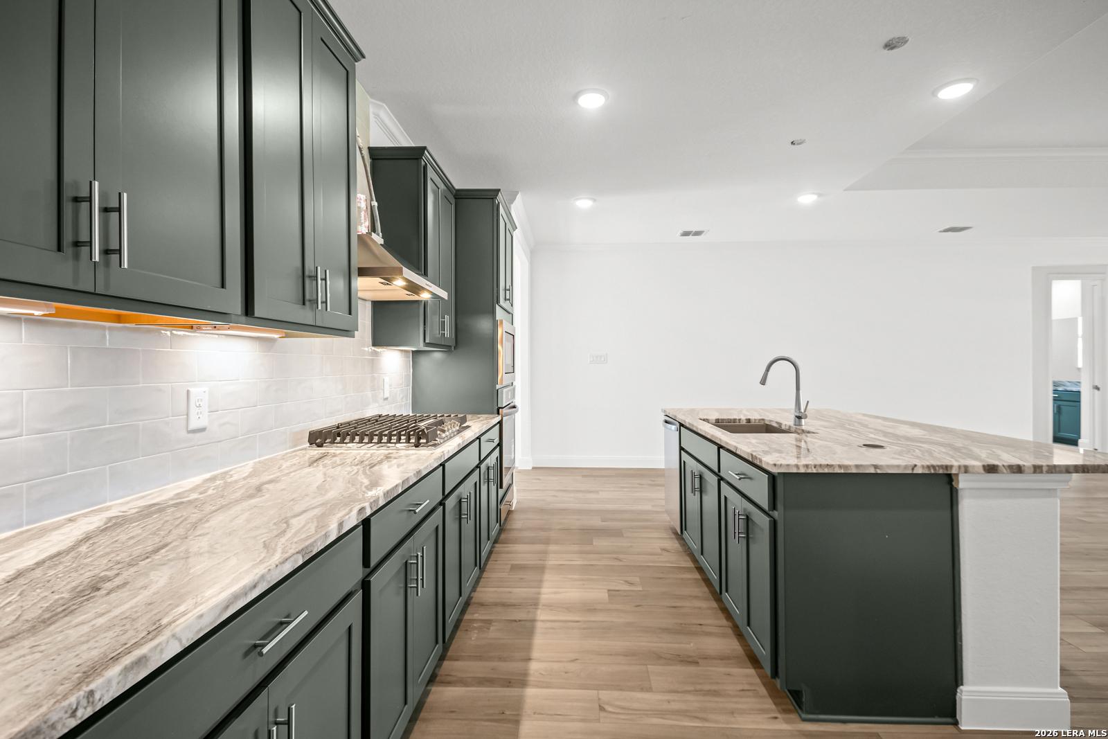 Modern kitchen with dark green cabinets, marble countertops, and island in The Lanier G plan at The Reserve at Potranco Oaks.