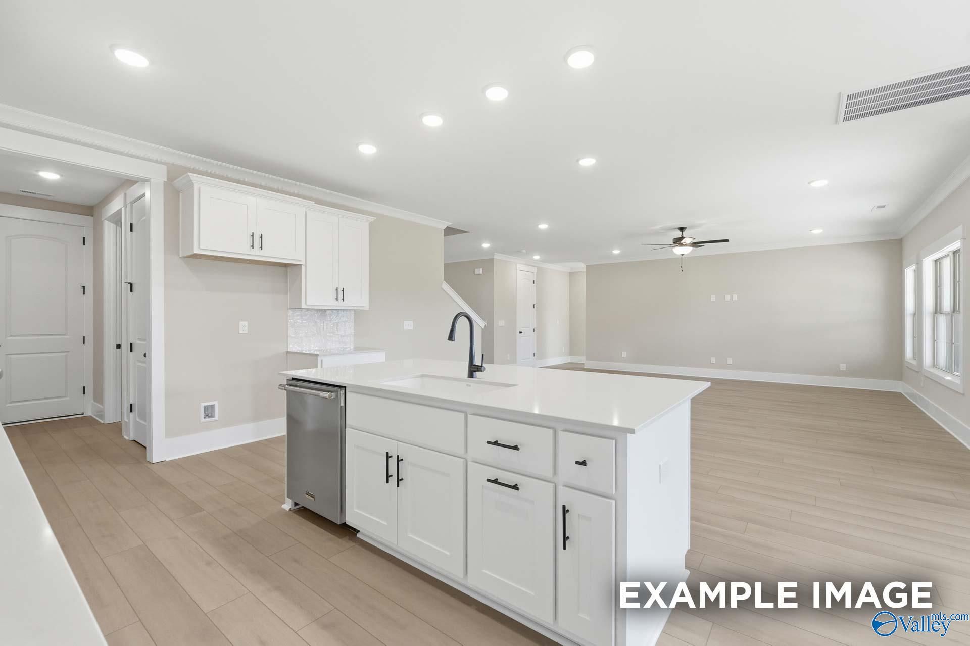 Modern open-concept kitchen with white island, stainless sink, and dishwasher in Davidson Homes The Emory, Decatur, AL