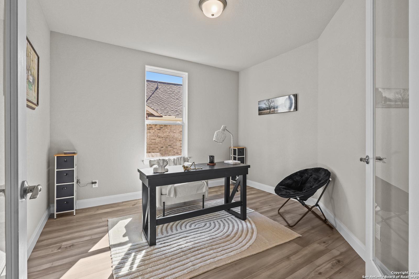 Modern home office with black desk, arched chair, bookshelves, and large window in Davidson Homes The Jennings G, Castroville, Texas