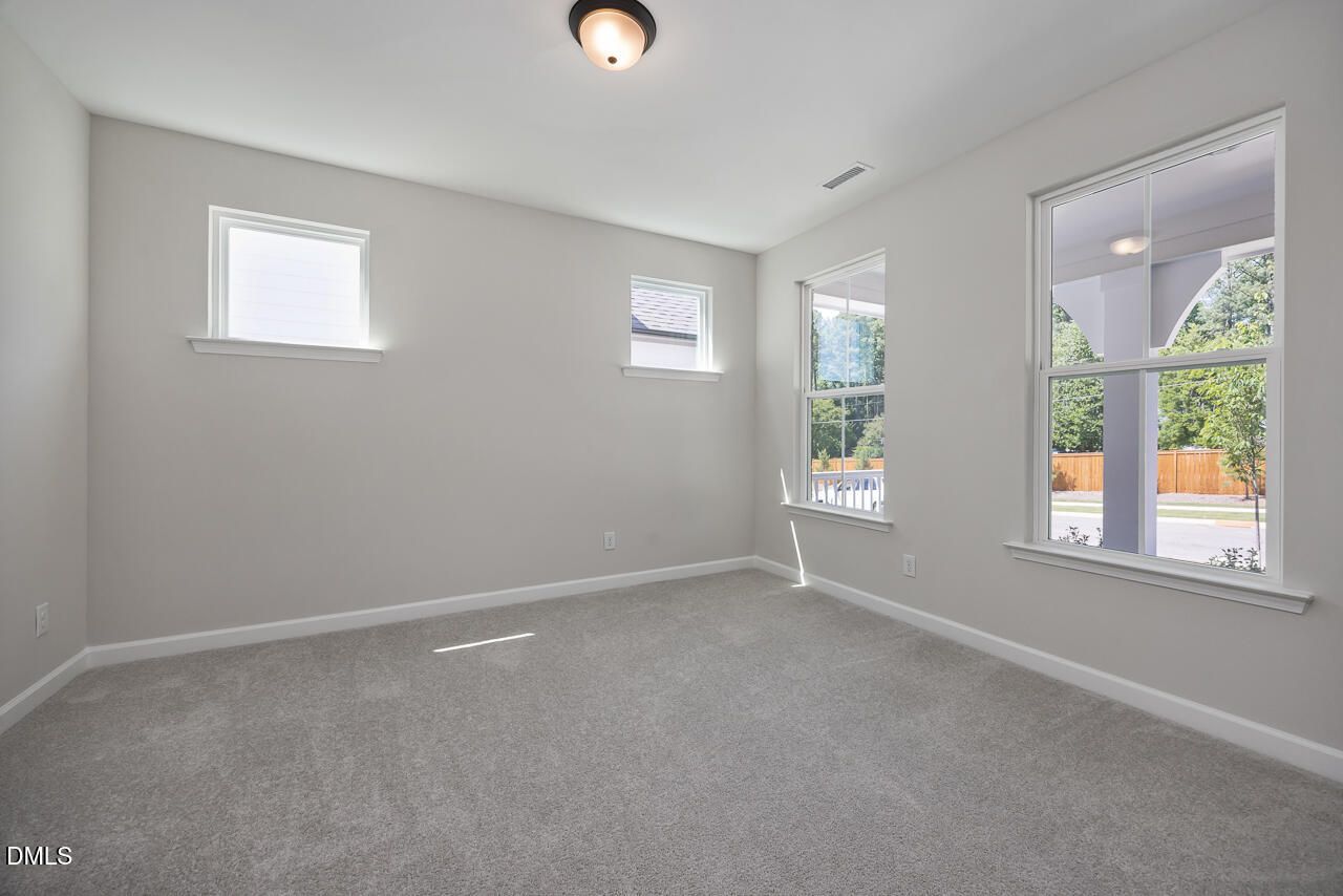 Bright, carpeted bedroom with large windows in The Ashport L floor plan at Sage on North Main, Wake Forest, NC.