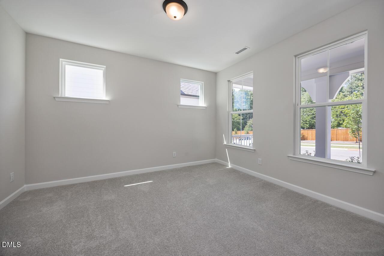 Bright, carpeted bedroom with large windows in The Ashport L floor plan at Sage on North Main, Wake Forest, NC.