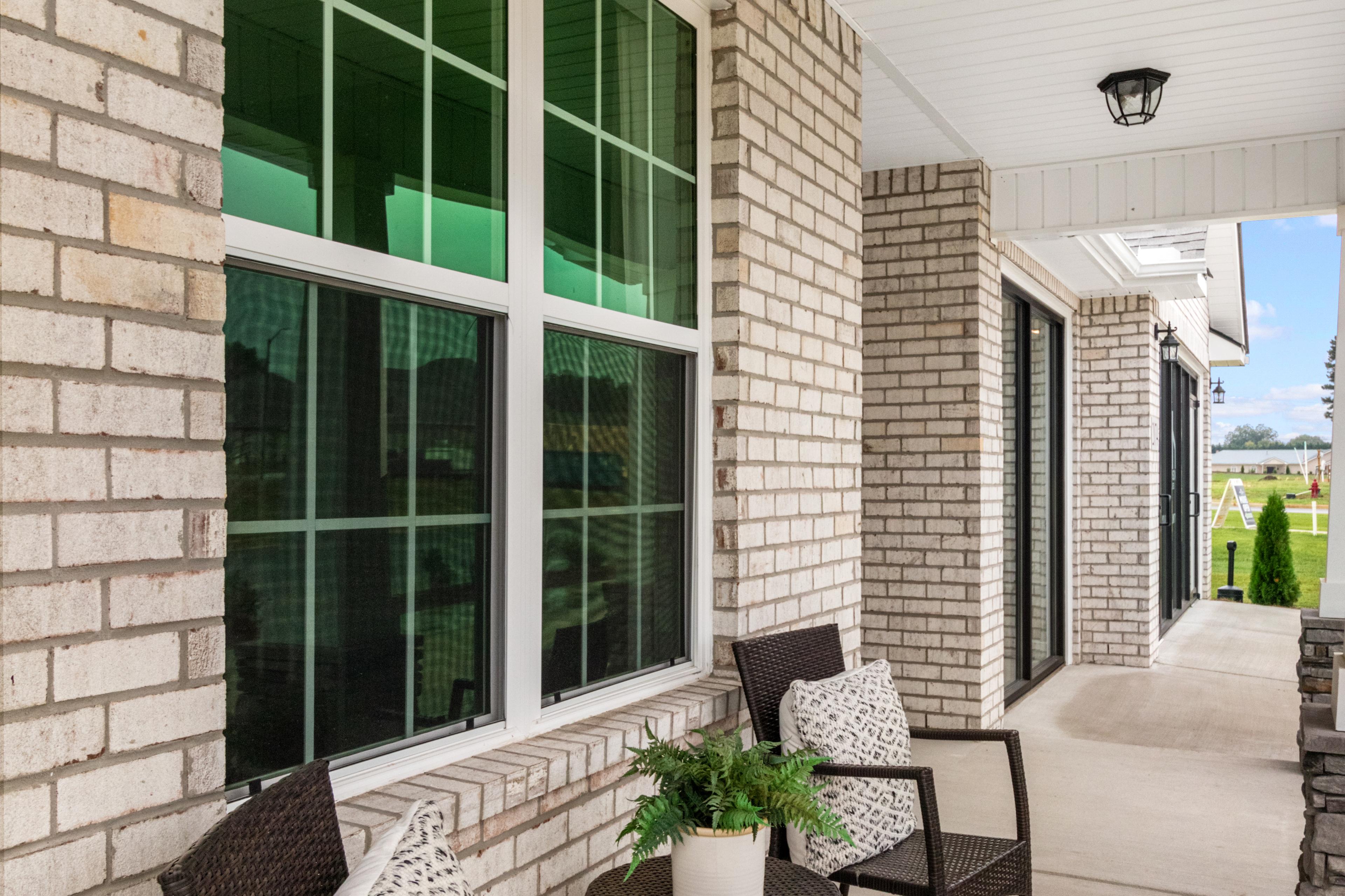 Cozy covered porch at North Ridge in Cullman Alabama with beige brick walls, wicker chairs, and potted plant
