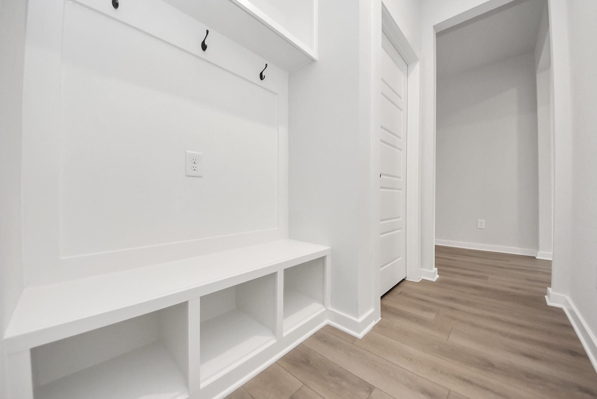 White mudroom drop zone with built-in bench and storage in The Daphne F floor plan at Sundance Cove, Crosby, Texas.