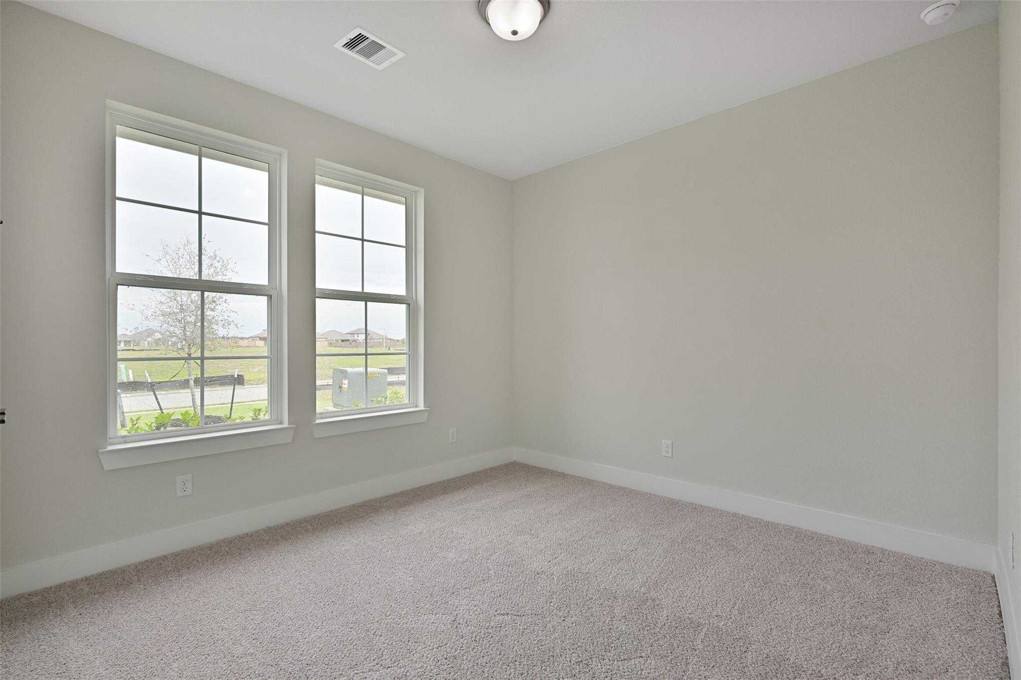 Bright empty bedroom with large windows and beige carpet in Davidson Homes The Edward C, Lago Mar, Texas City