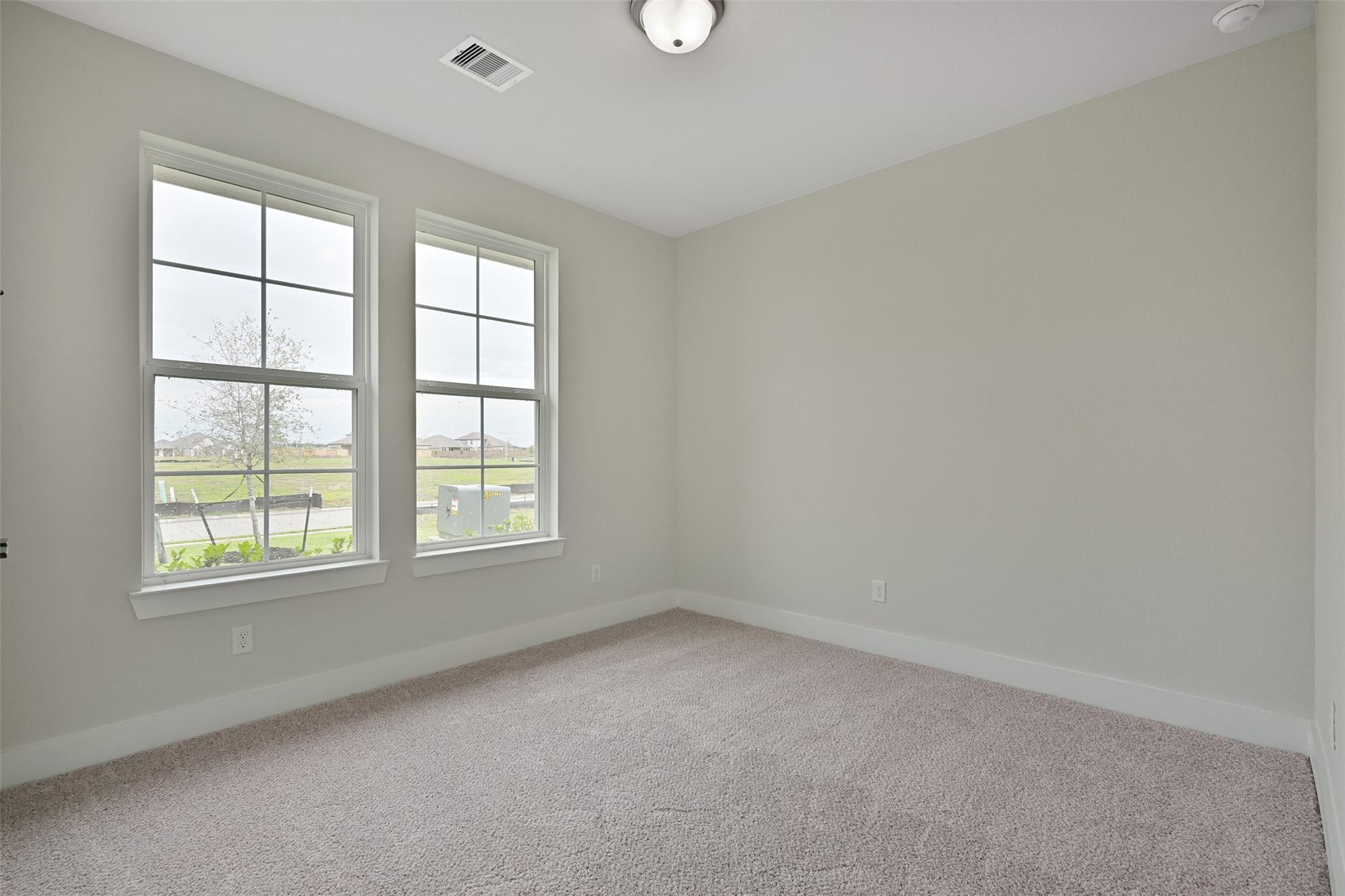 Bright empty bedroom with large windows and beige carpet in Davidson Homes The Edward C, Lago Mar, Texas City