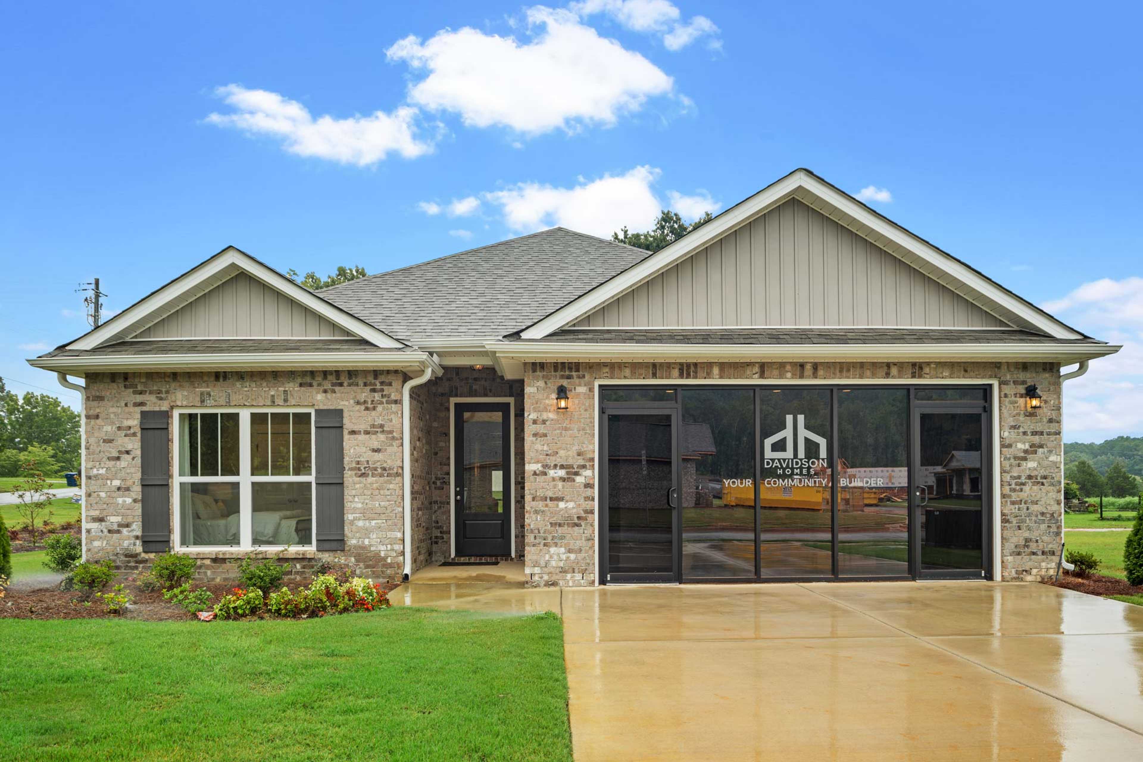 Craftsman-style home exterior at Monteagle Cove in Owens Cross Roads AL with gray siding, brick accents, and two-car garage by Davidson Homes