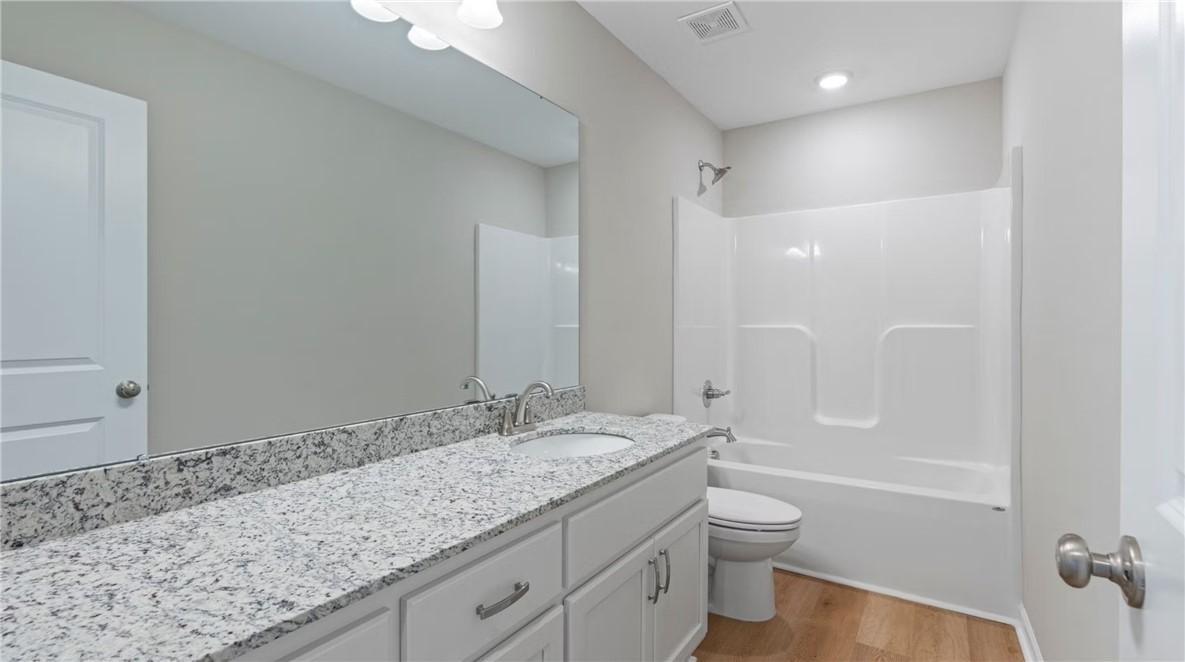 Modern bathroom with double granite vanity, tub-shower combo, and white cabinets in Evermore Homes The Stella D, Cusseta, Alabama