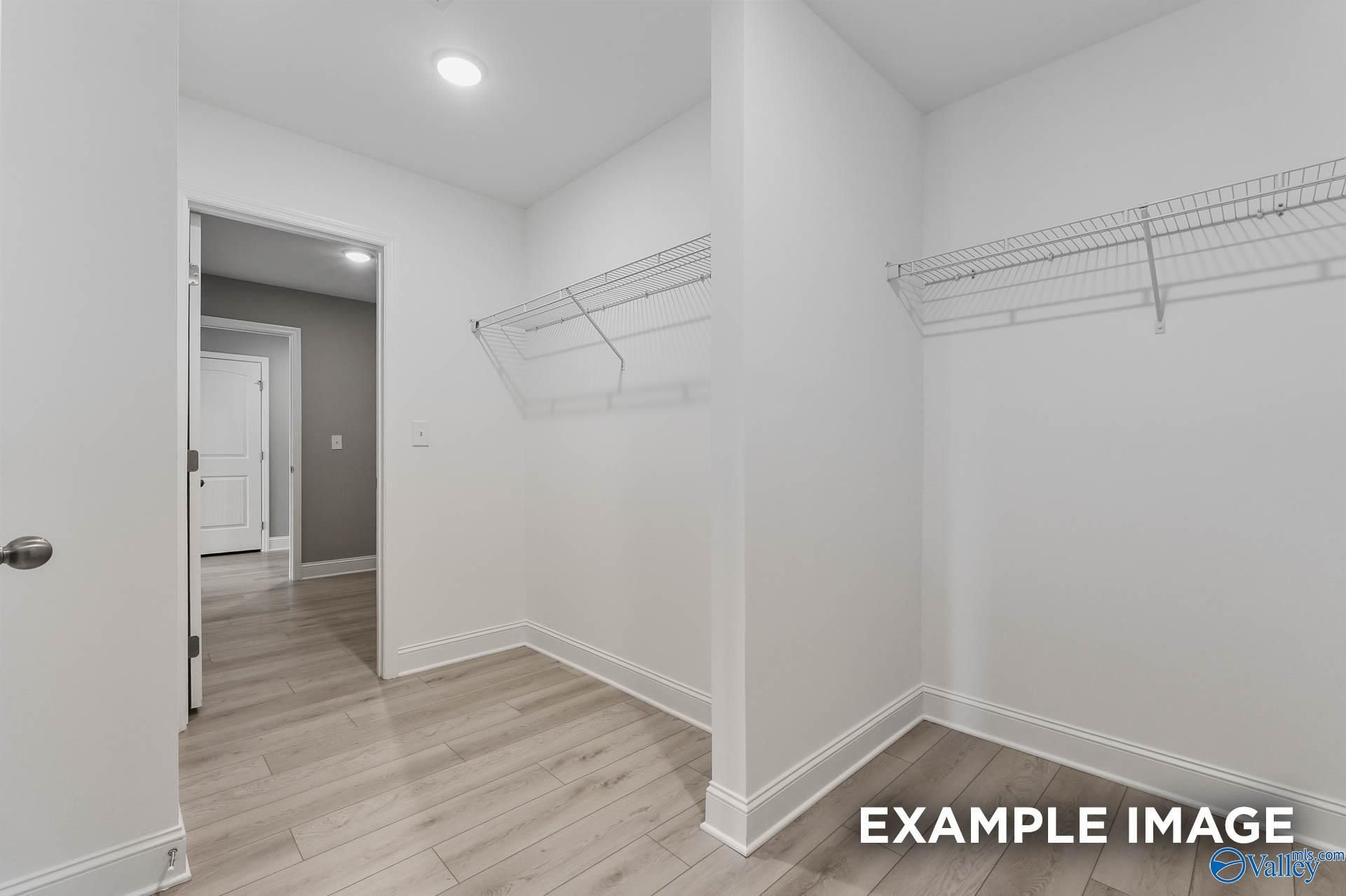Spacious walk-in closet with wire shelving and white walls in master suite of The Everett B by Davidson Homes, Toney, Alabama