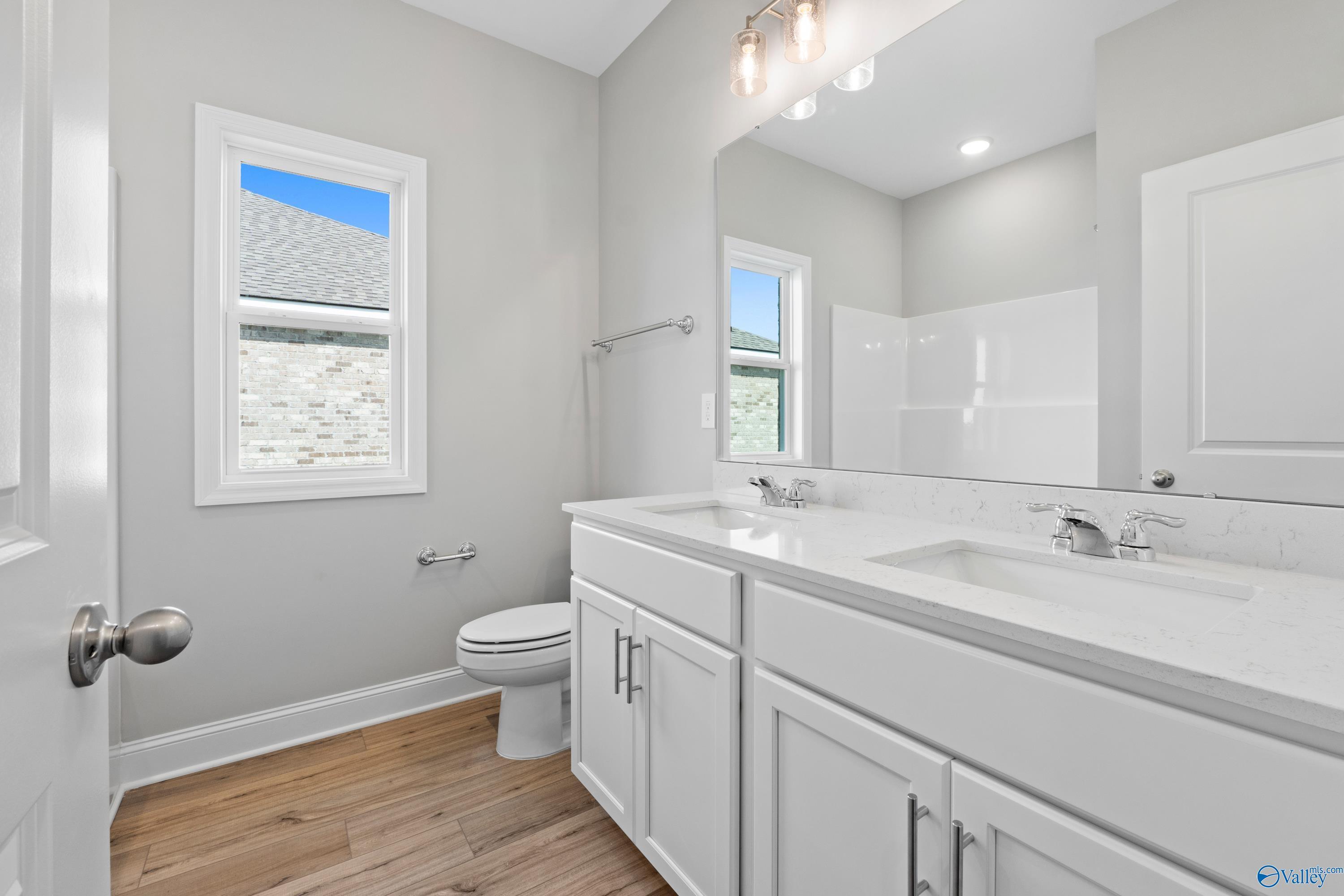 Modern master bathroom with white double vanity, tiled shower, and skylit window in Davidson Homes Everett B, Toney, Alabama