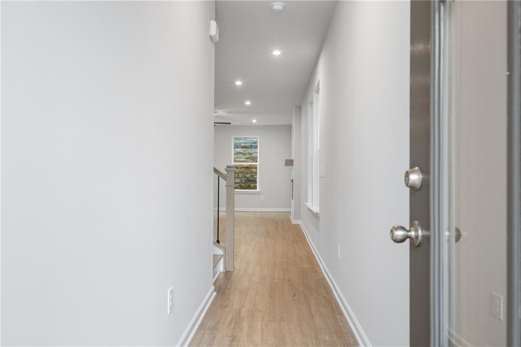 Bright hallway with hardwood floors, white walls, staircase, and landscape art in Davidson Homes The Cary A, Kennesaw, Georgia