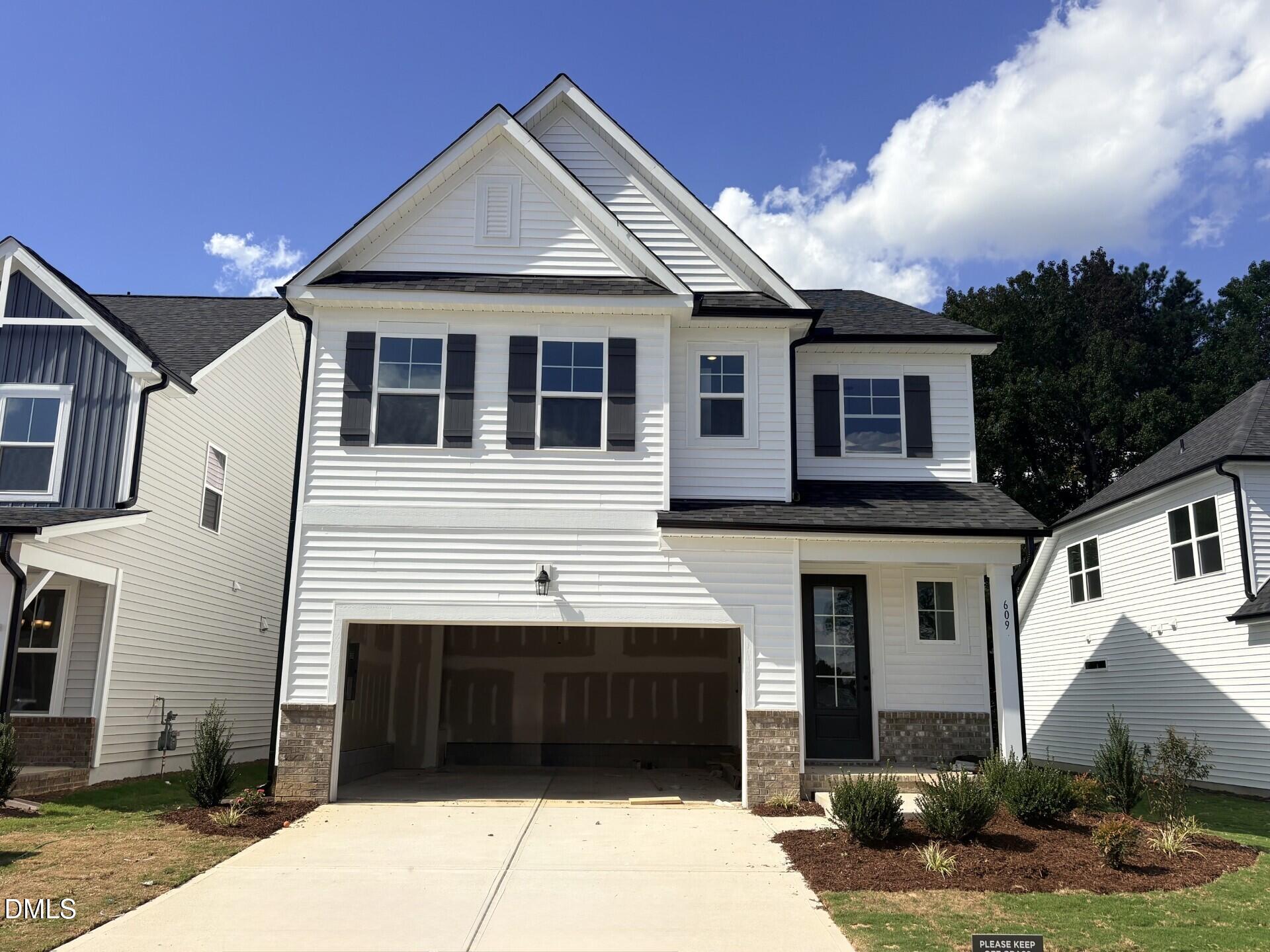 White 2-story new construction home with 2-car garage and black shutters at Woodland Crossing, Zebulon NC by Davidson Homes