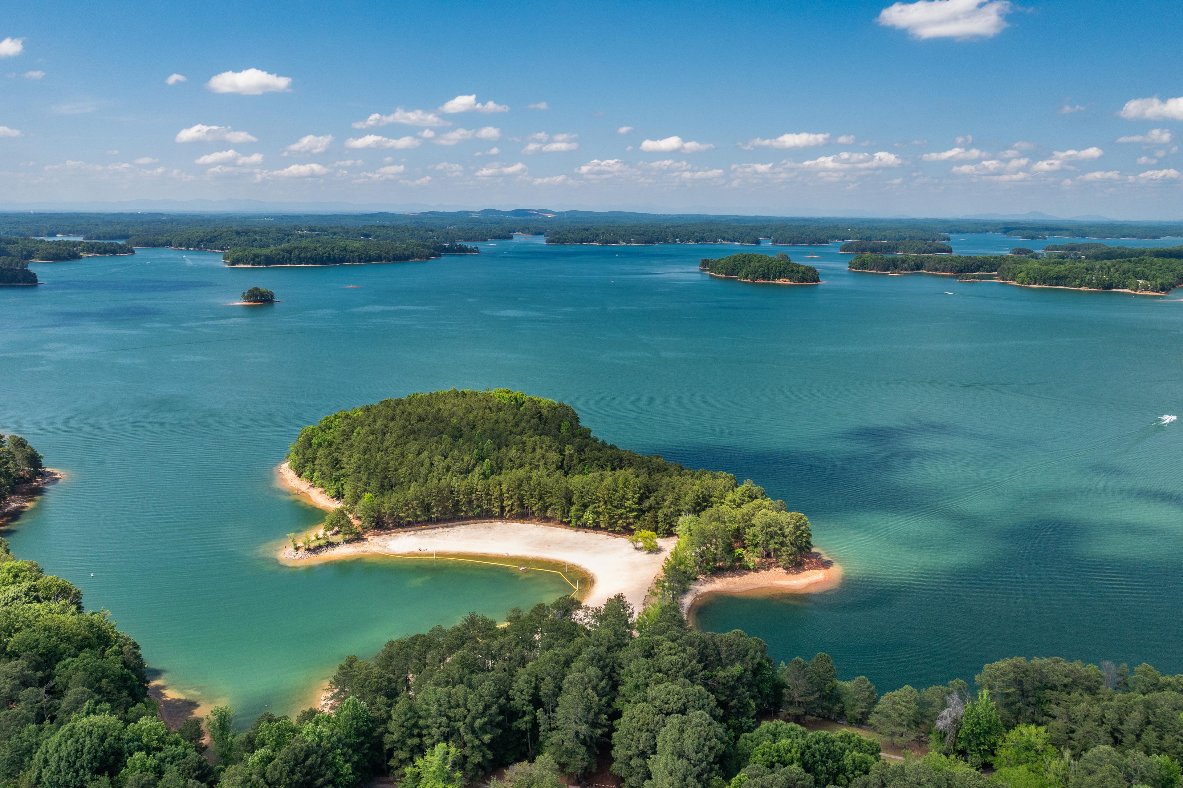 Aerial view of Lake Lanier near Melody Lakeside Estates in Buford, GA, featuring a sandy beach and forested shoreline.