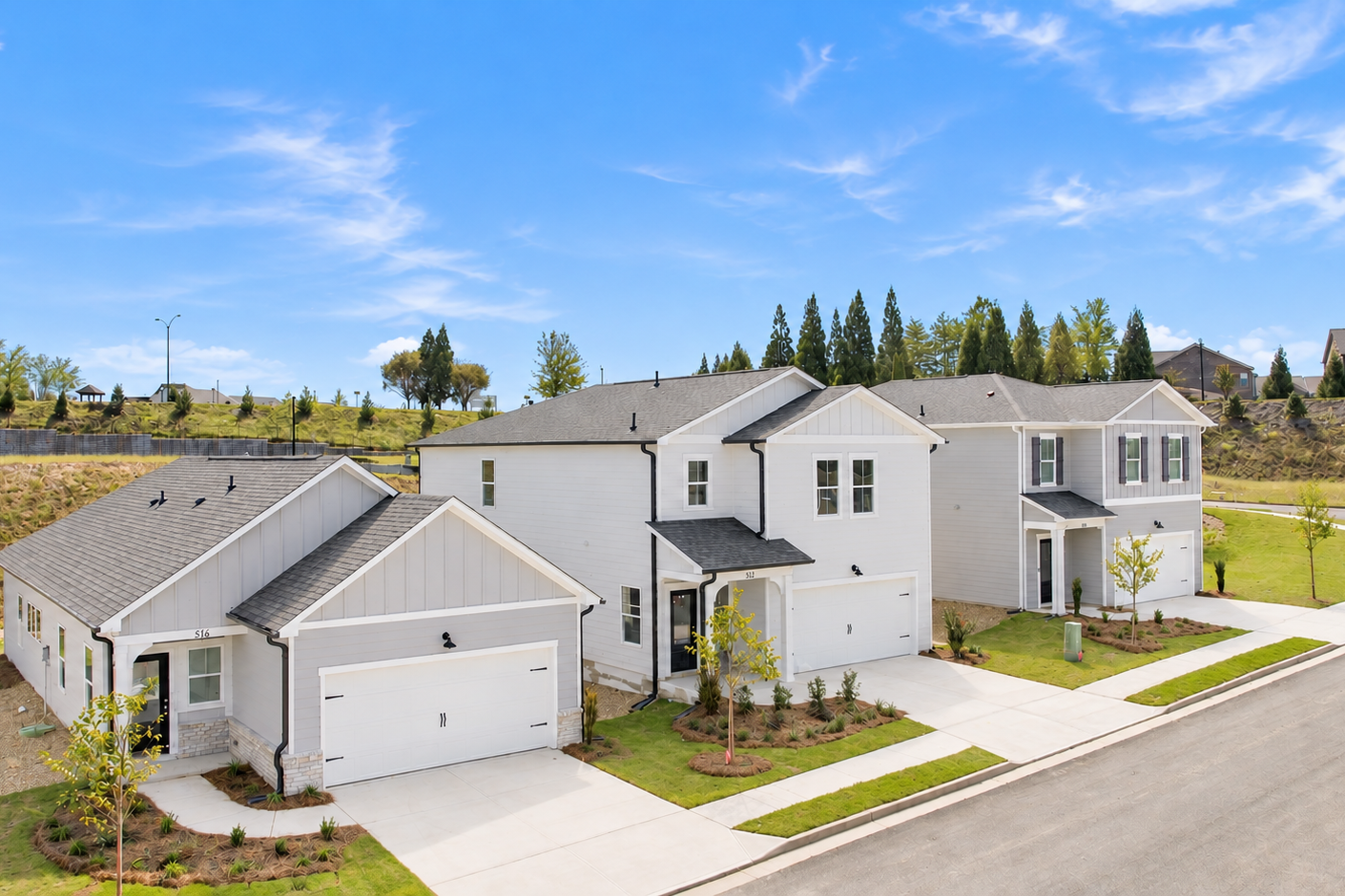 New homes at The Bluffs in Canton, Georgia by Davidson Homes, featuring gray siding, white garages, and landscaped front yards