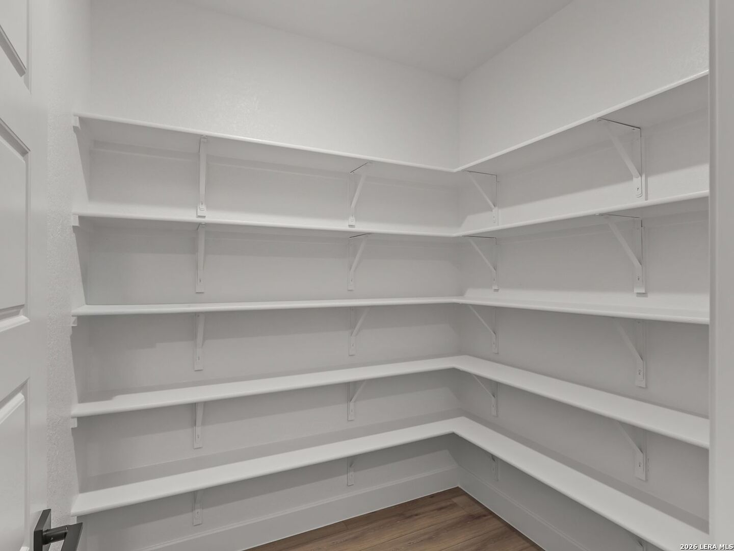 Walk-in pantry with white wrap-around shelving in a Davidson Homes Belmont floor plan in Potranco Oaks, Castroville, TX.