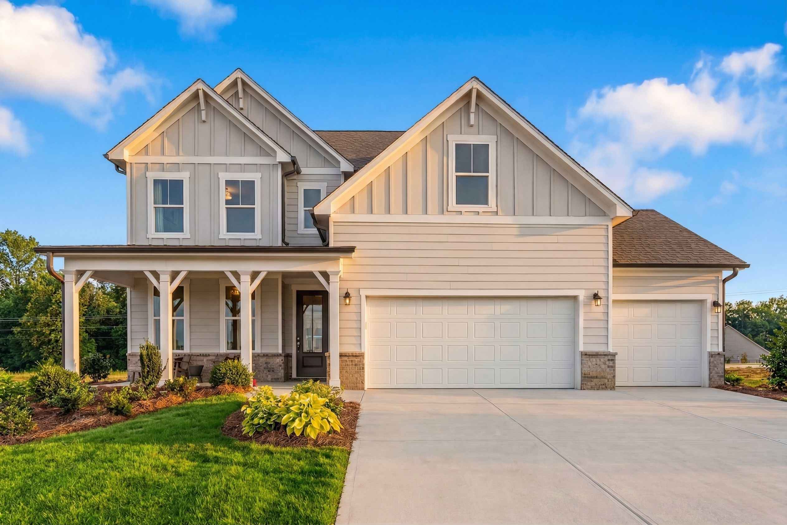 Modern farmhouse home exterior at Wehunt Meadows in Hoschton GA with covered porch, large windows, and lush landscaping