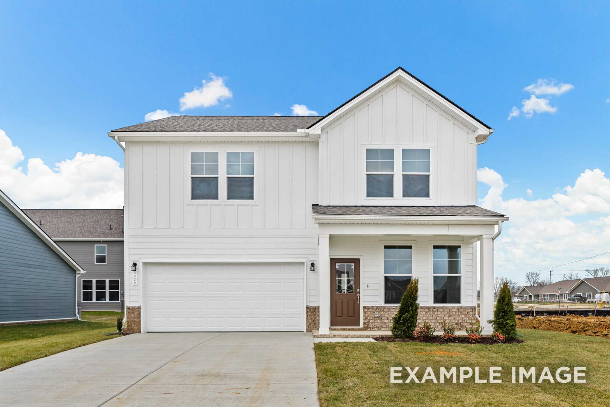 Two-story The Logan C home design with white board-and-batten siding, covered front porch, two-car garage, and landscaped yard in White House, TN
