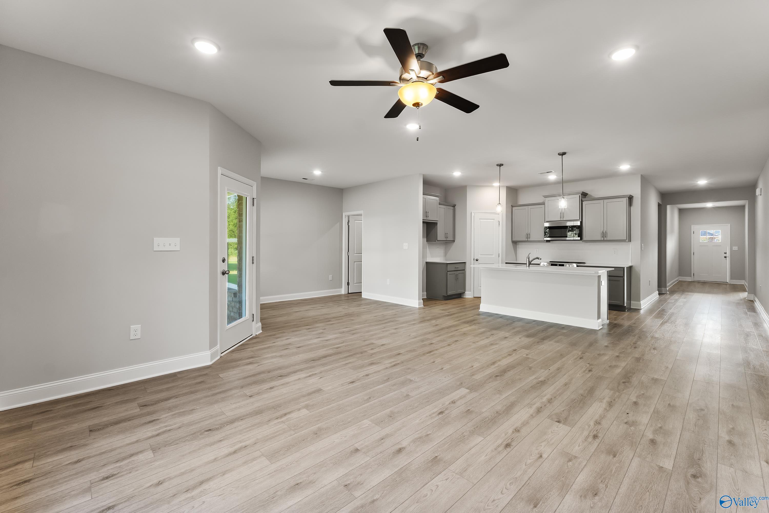 Spacious open-concept kitchen and living area with wood floors, white cabinets, stainless appliances, and French doors in The Daphne C, Huntsville, AL
