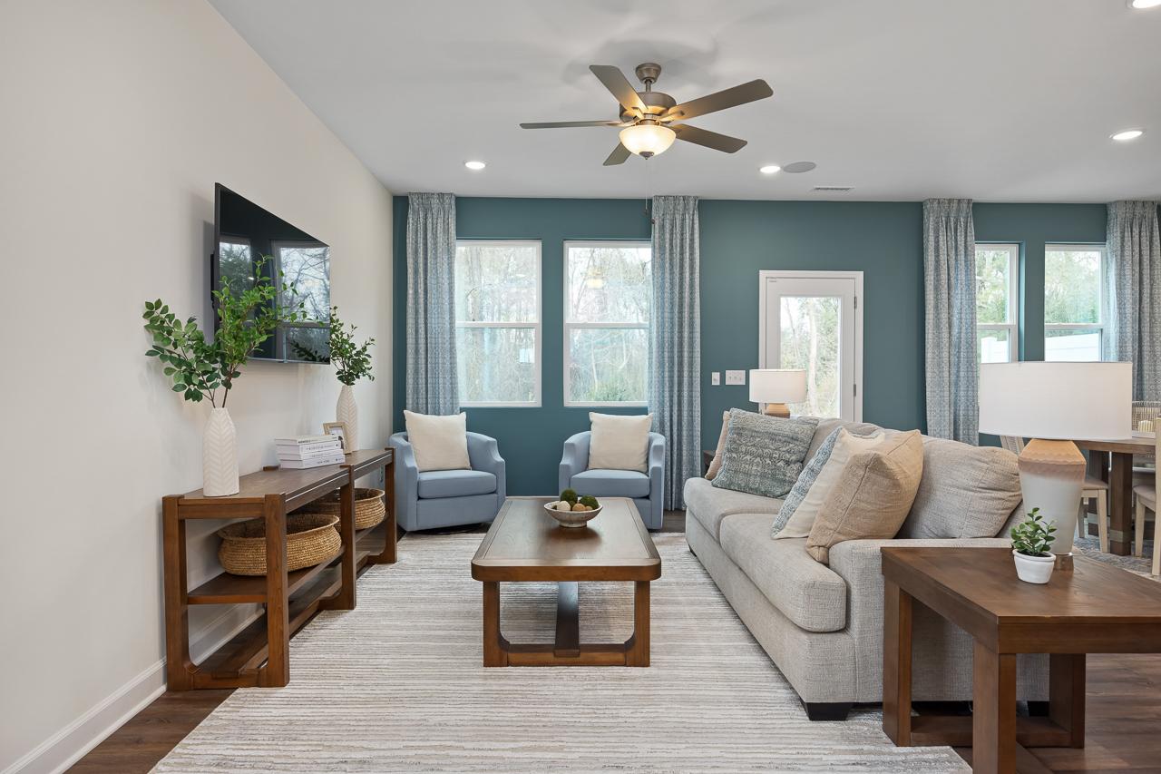 Cozy living room at Gregory Village Townhomes in Lillington NC featuring gray sofa, blue armchairs, wooden coffee table, and large curtained windows