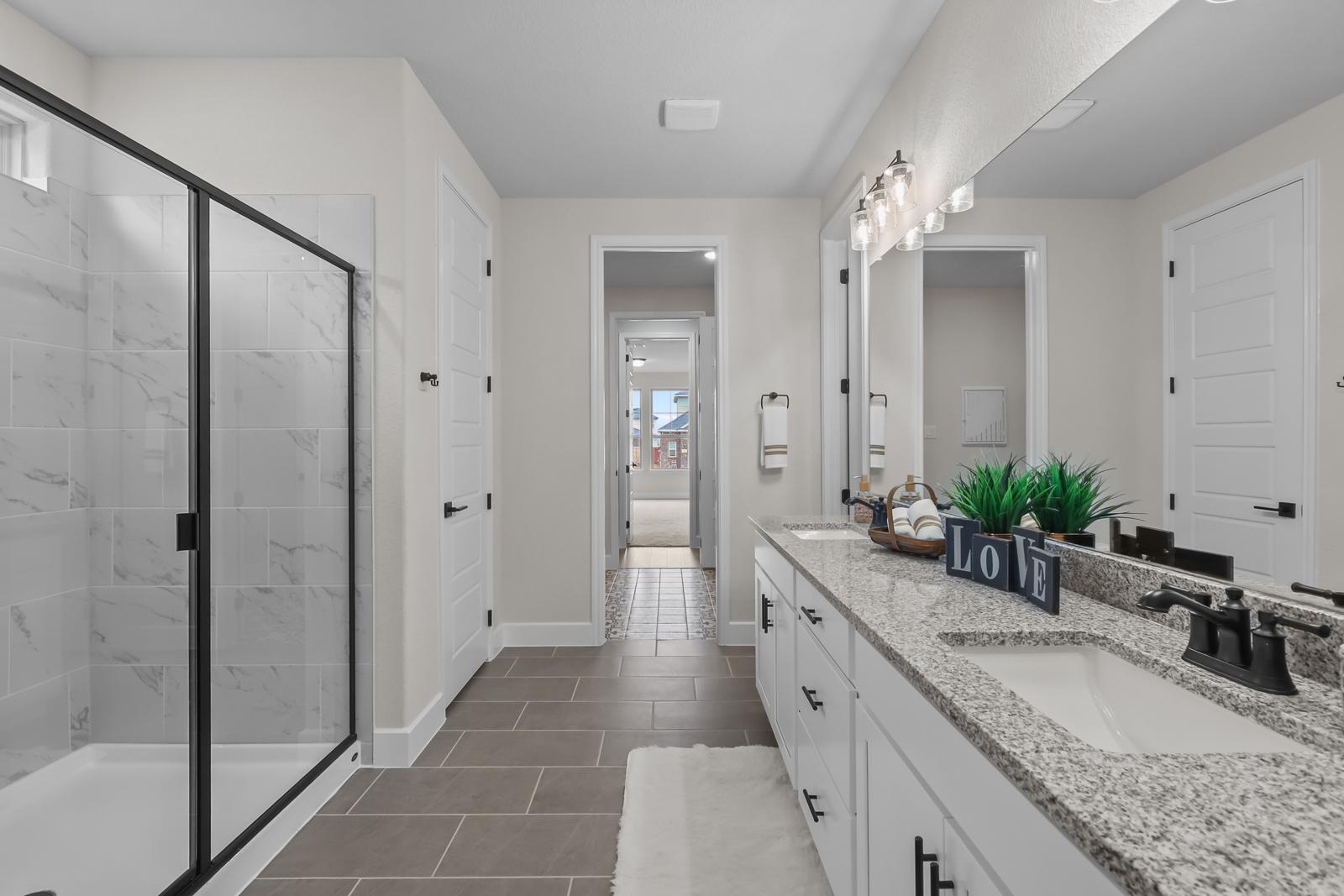 Spacious master bathroom in The Belmont J featuring a glass walk-in shower, dual vanity, and modern finishes.