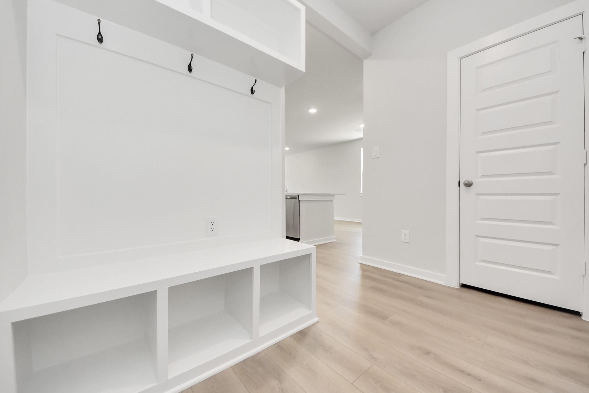 Built-in white mudroom bench with coat hooks in The Blanco F floor plan at Spring Branch Crossing, Conroe, Texas.