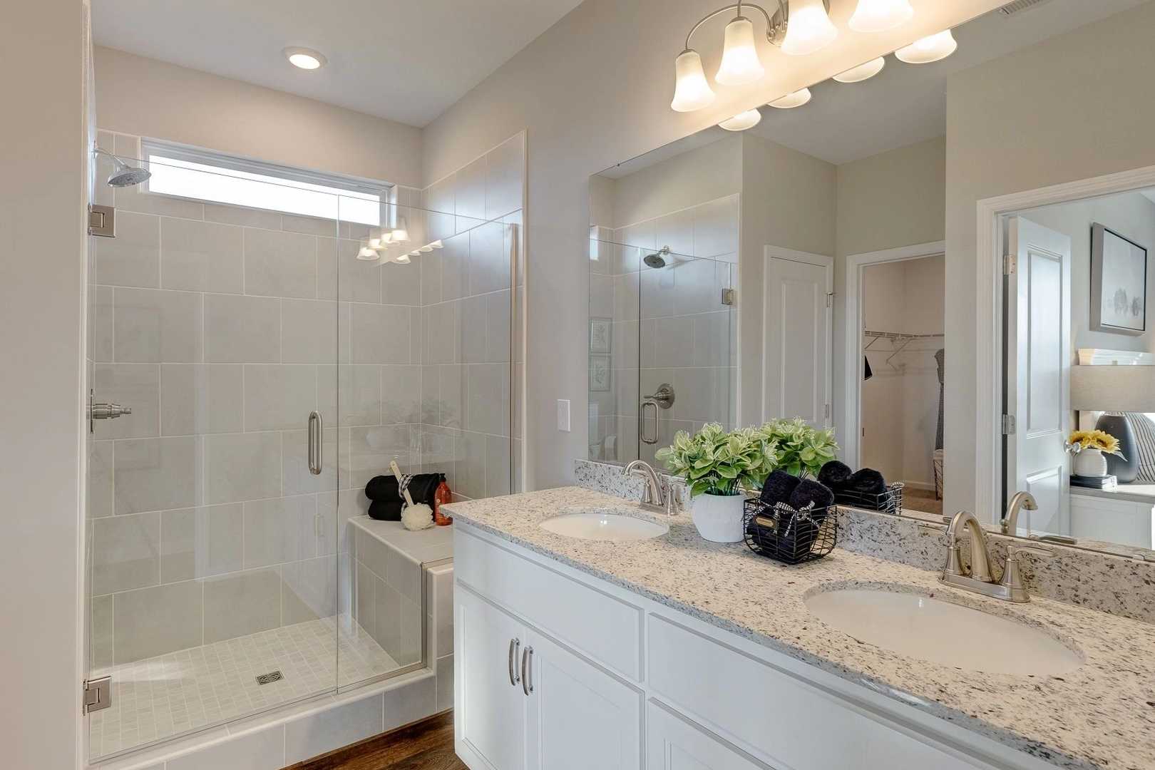Modern primary bathroom in Carroll Green Harvest Alabama with double vanity white quartz countertop glass walk-in shower and neutral tones