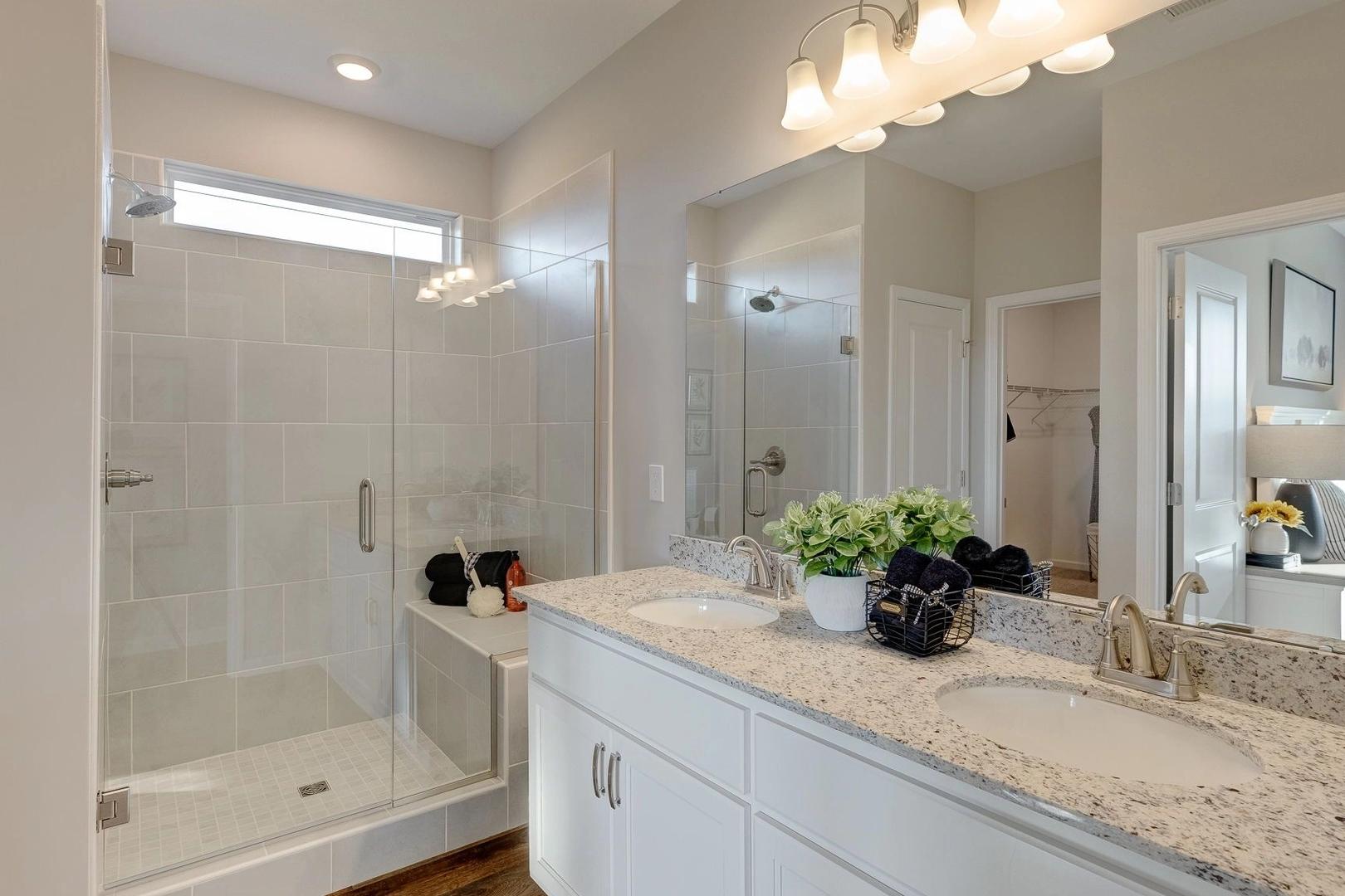 Modern primary bathroom in Carroll Green Harvest Alabama with double vanity white quartz countertop glass walk-in shower and neutral tones