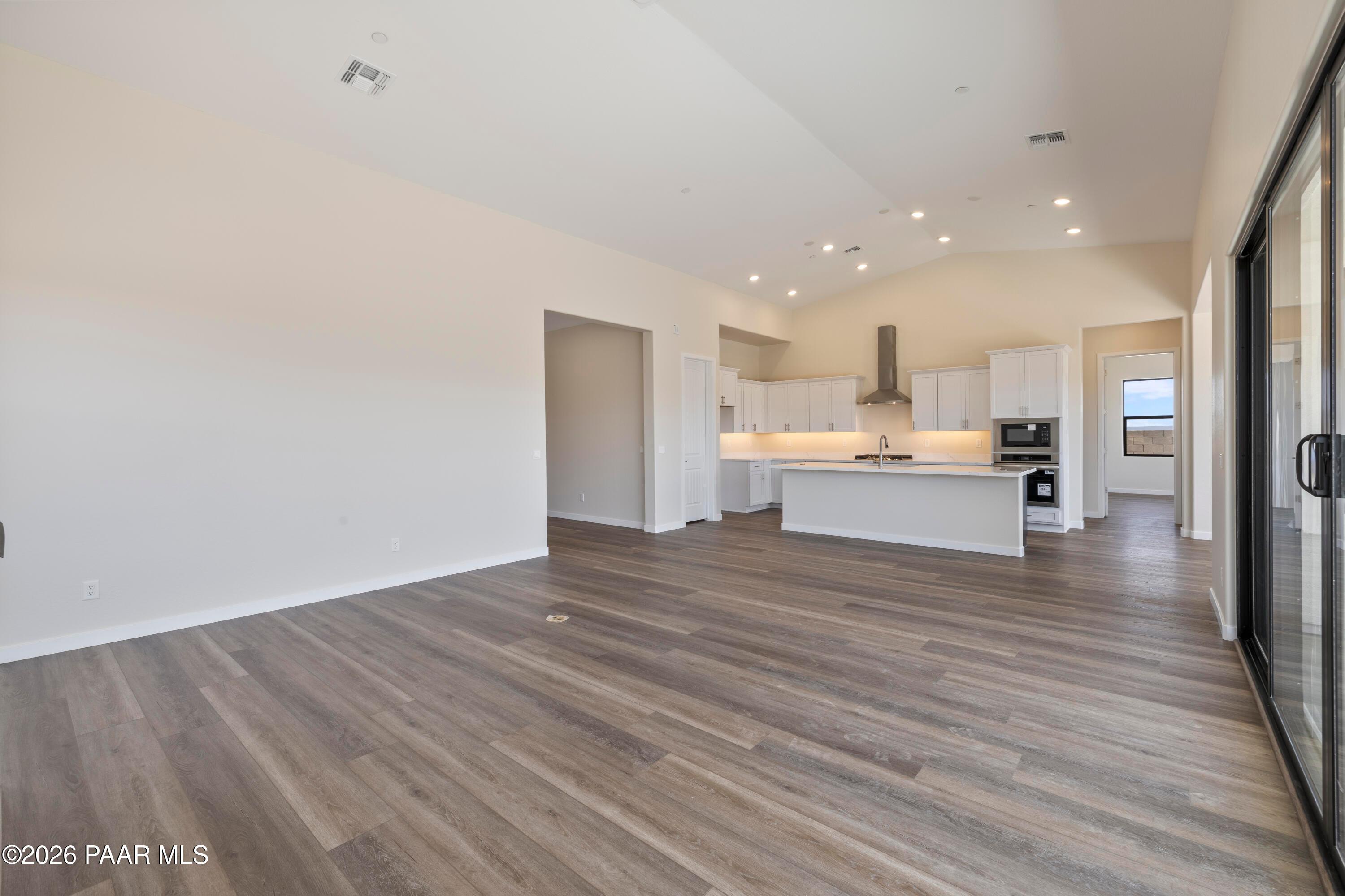 Modern open-concept kitchen with white cabinets, large island, stainless appliances, and sliding doors in Davidson Homes Soleil E, Prescott AZ