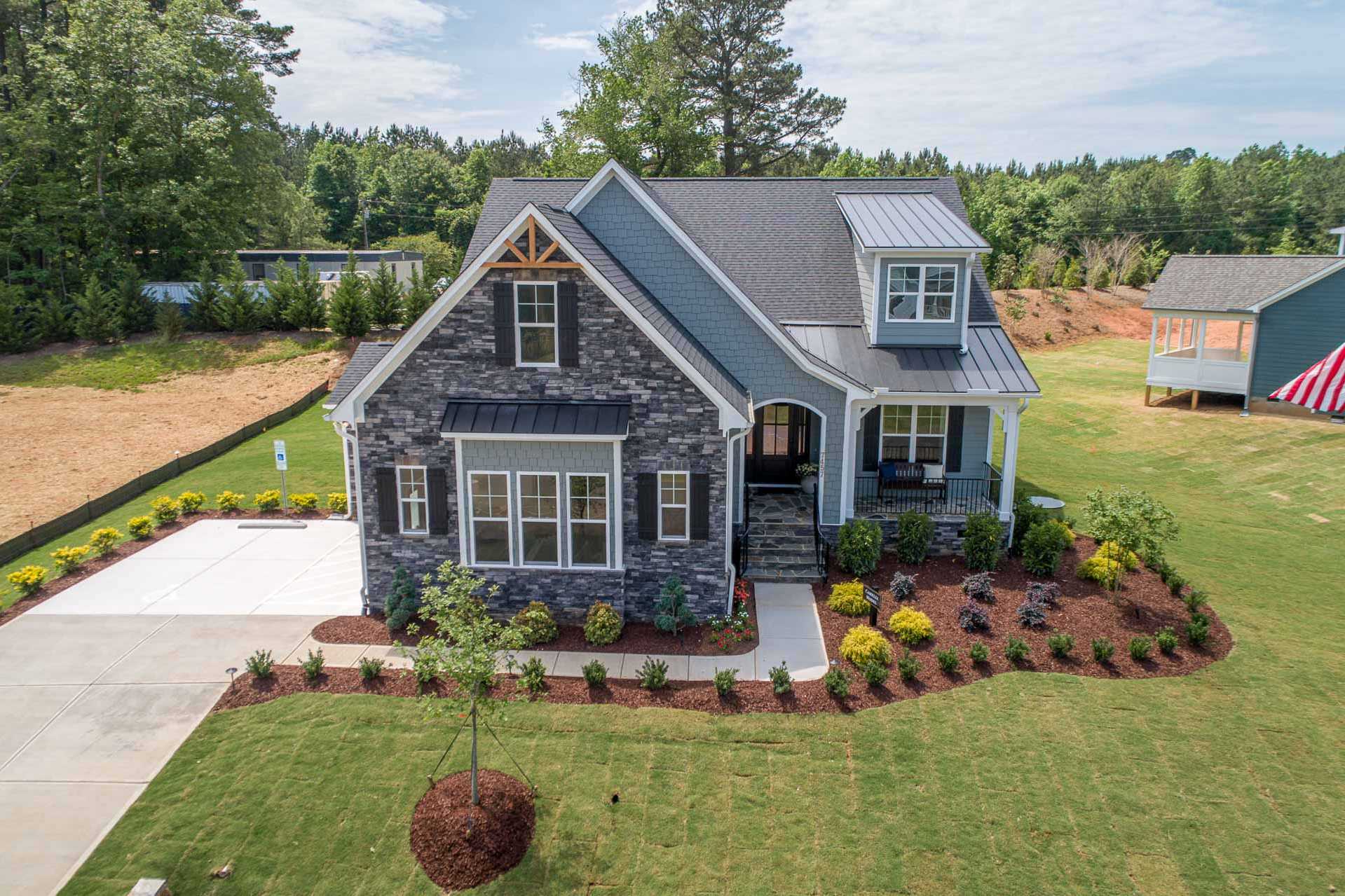 Craftsman-style home exterior at Hasentree in Wake Forest NC with gray stone facade, covered porch, and landscaped yard