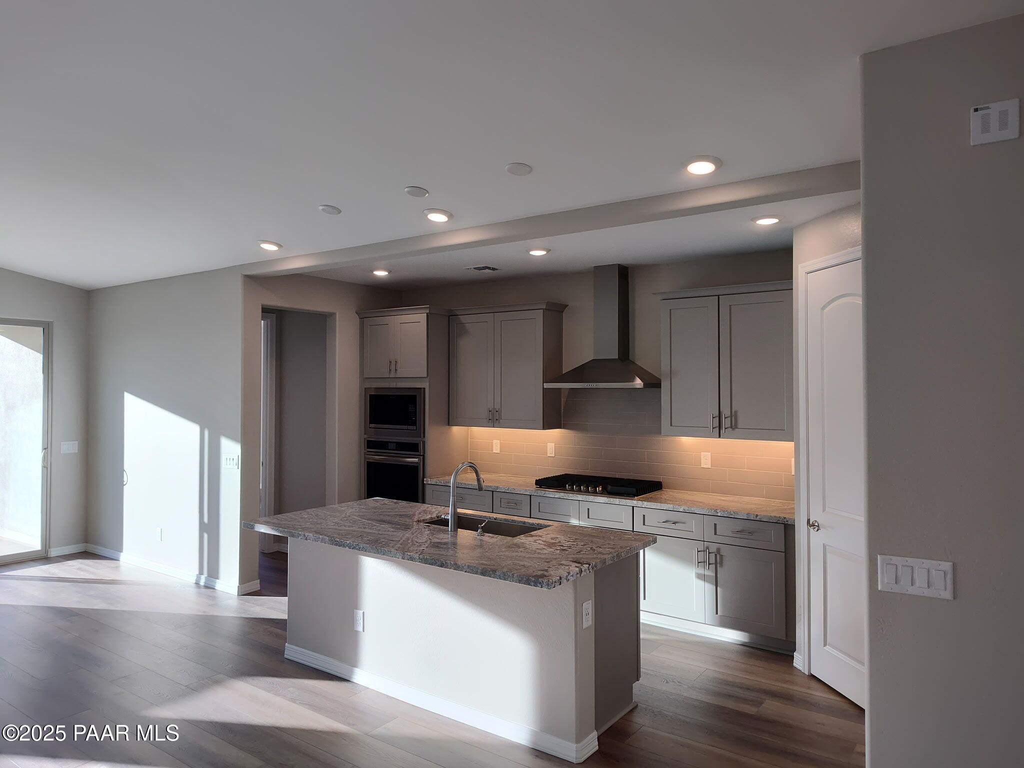 Modern open-concept kitchen with gray cabinets, granite island, and stainless appliances in Davidson Homes The Frontier C, Prescott Valley, AZ