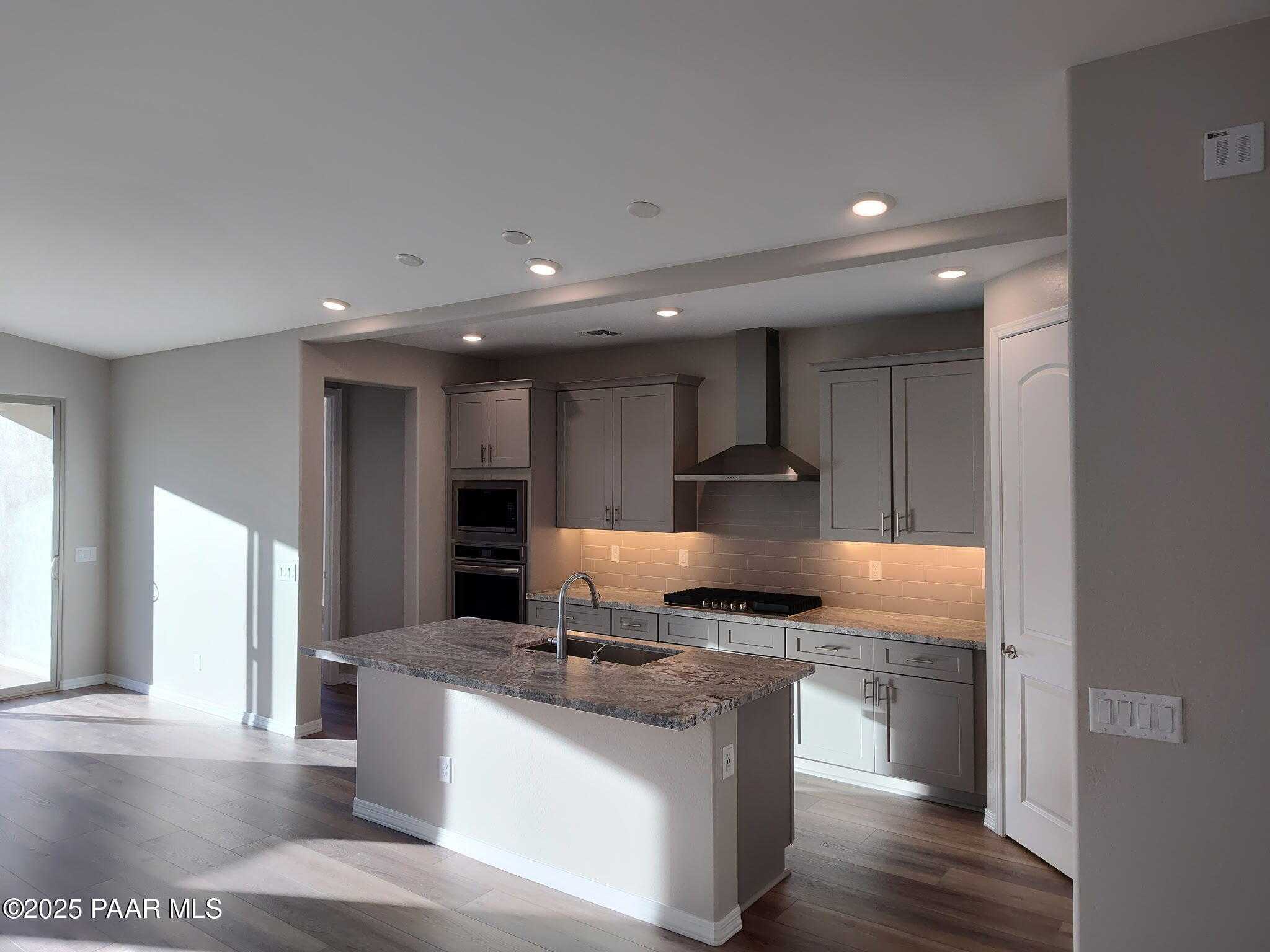 Modern open-concept kitchen with gray cabinets, granite island, and stainless appliances in Davidson Homes The Frontier C, Prescott Valley, AZ