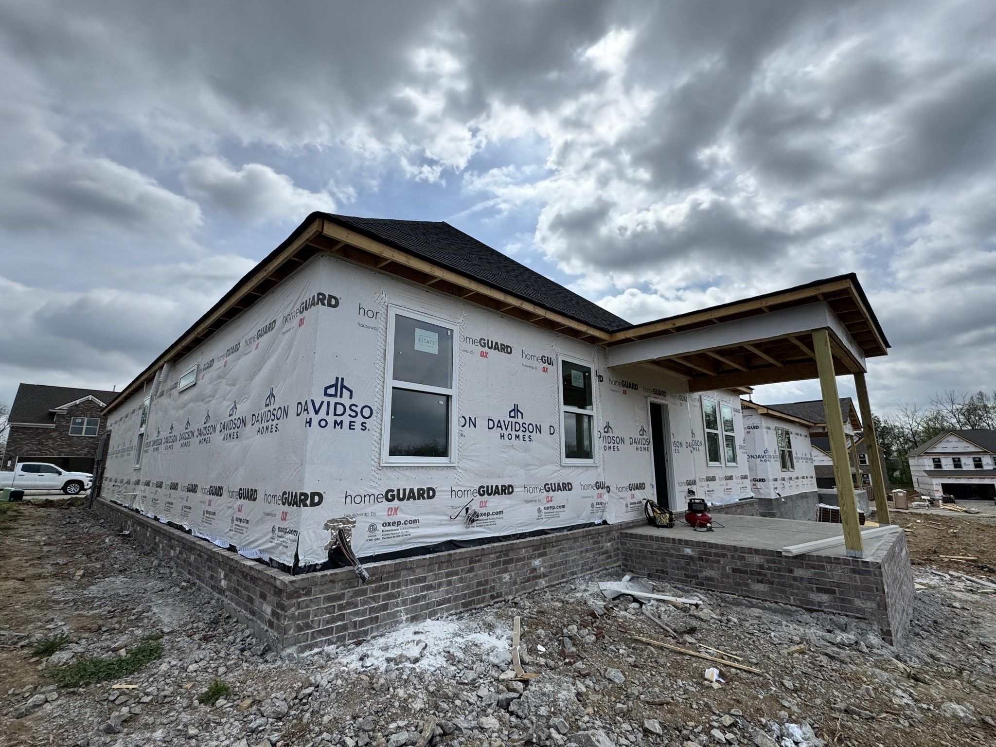 New construction single-story home with brick foundation, covered porch, and Davidson Homes branding in Woods Crossing, Gallatin, Tennessee