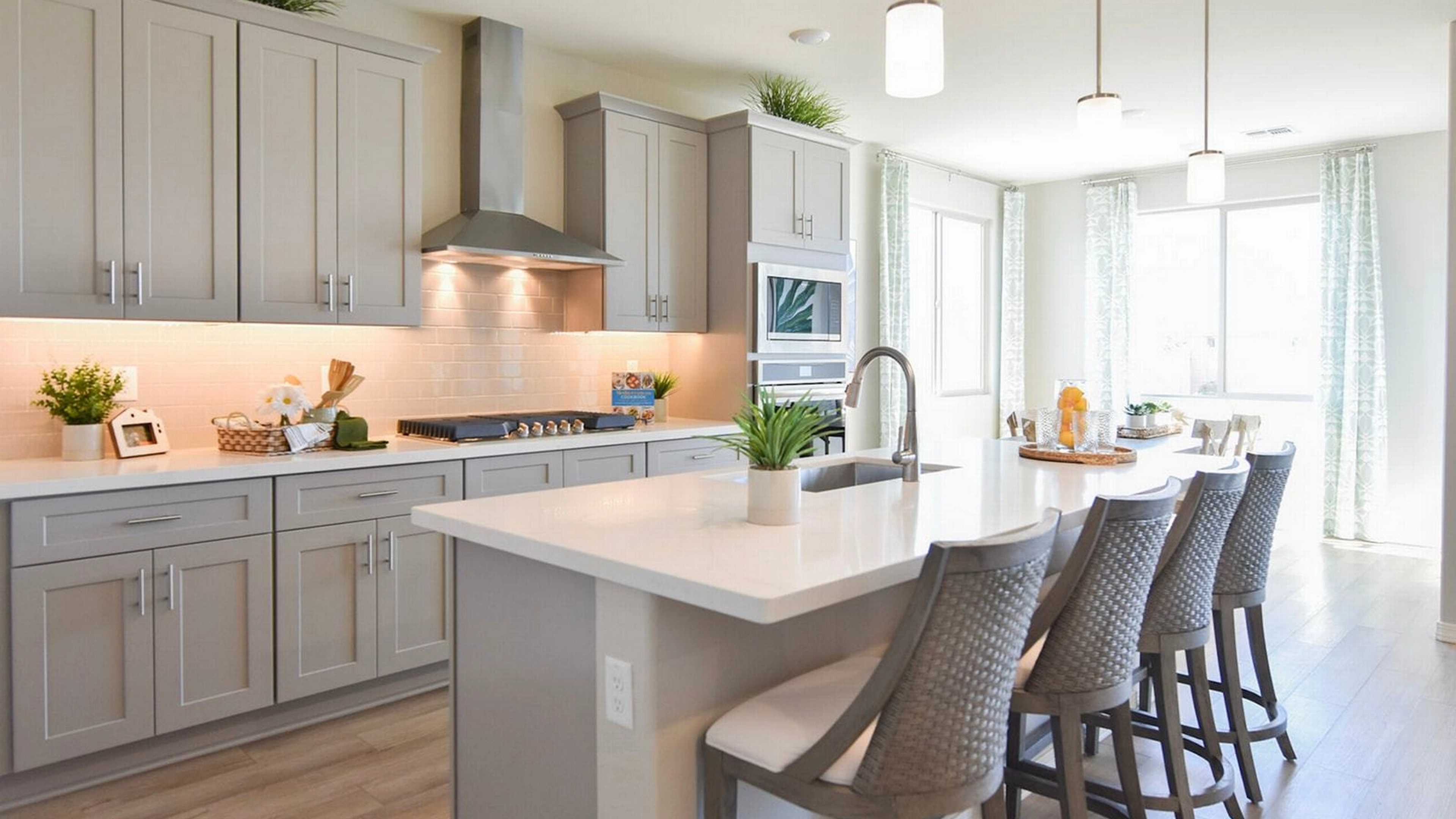 Contemporary kitchen with gray shaker cabinets, white quartz island, bar stools, and stainless appliances at North Ridge Pronghorn Ranch in Prescott Valley AZ