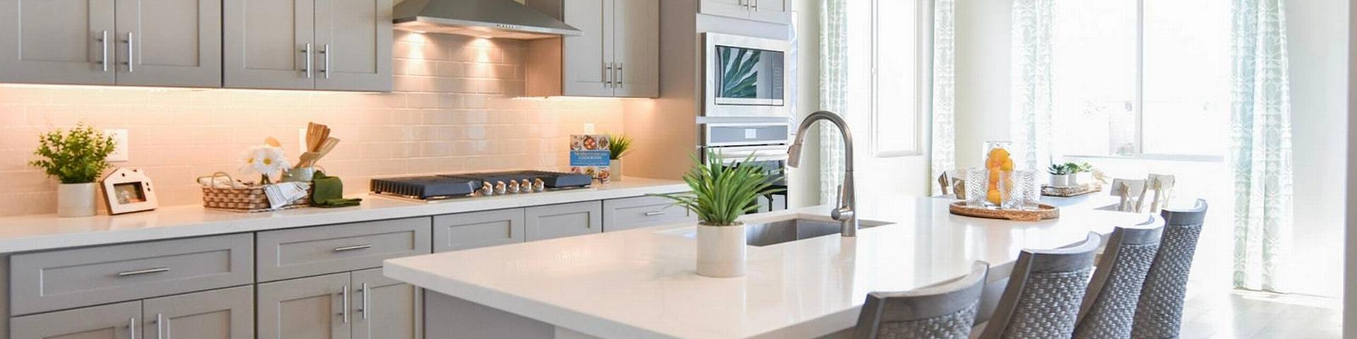 Contemporary kitchen with gray shaker cabinets, white quartz island, bar stools, and stainless appliances at North Ridge Pronghorn Ranch in Prescott Valley AZ