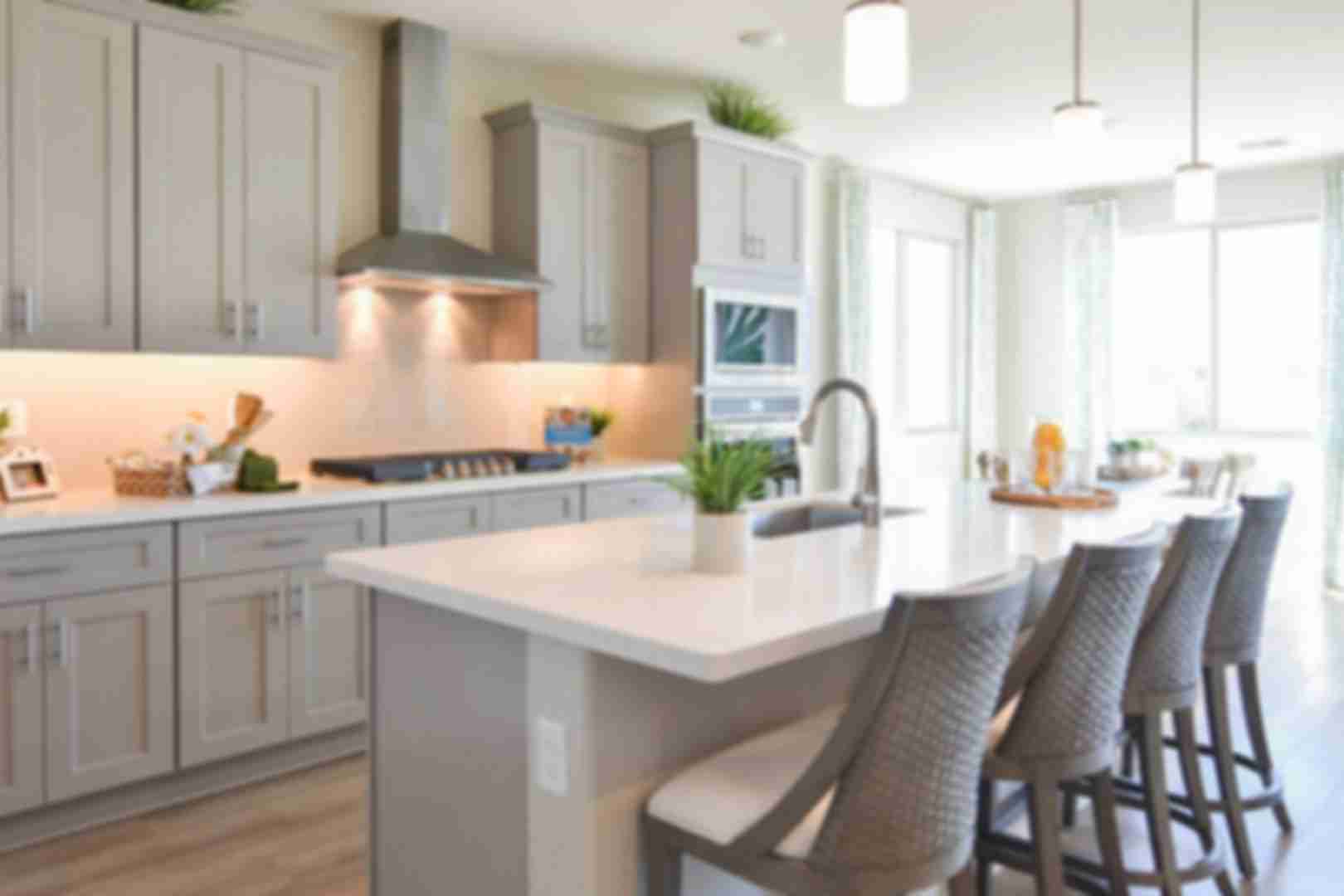 Contemporary kitchen with gray shaker cabinets, white quartz island, bar stools, and stainless appliances at North Ridge Pronghorn Ranch in Prescott Valley AZ